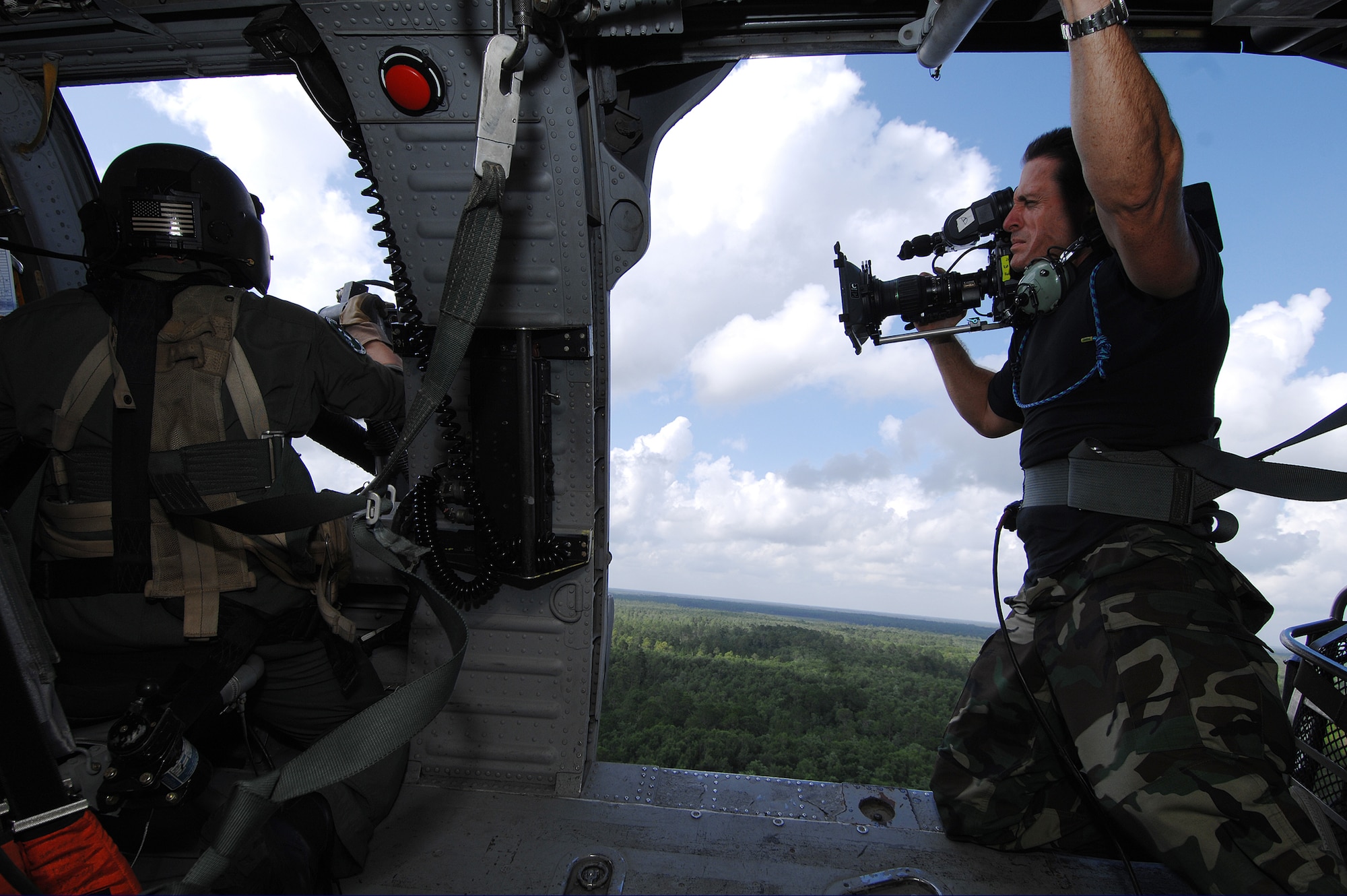 Jodi Miller, a commercial cinematographer with Bandito Brothers Films, videotapes Tech. Sgt. Joel Herbert, 41st Rescue Squadron flight engineer, firing his GAU-2 minigun from an HH-60G Pave Hawk helicopter, June 27 in the skies above Moody Air Force Base, Ga. A video production company visited Moody to film a commercial for the U.S. Air Force recruiting campaign, "Do Something Amazing." (U.S. Air Force photo by Master Sgt. Scott Reed)