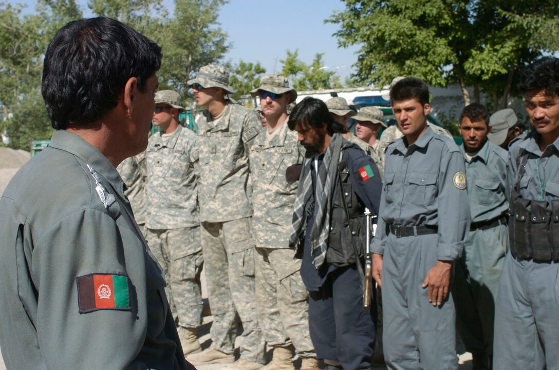 Qarabagh District Police Chief Col. Abdul Shokor, left, talks to Afghan policemen and U.S. Army soldiers during a formation at the Qarabagh District Center in Ghazni province, Afghanistan, June 16, 2007.  U.S. Army photo by Sgt. Jim Wilt