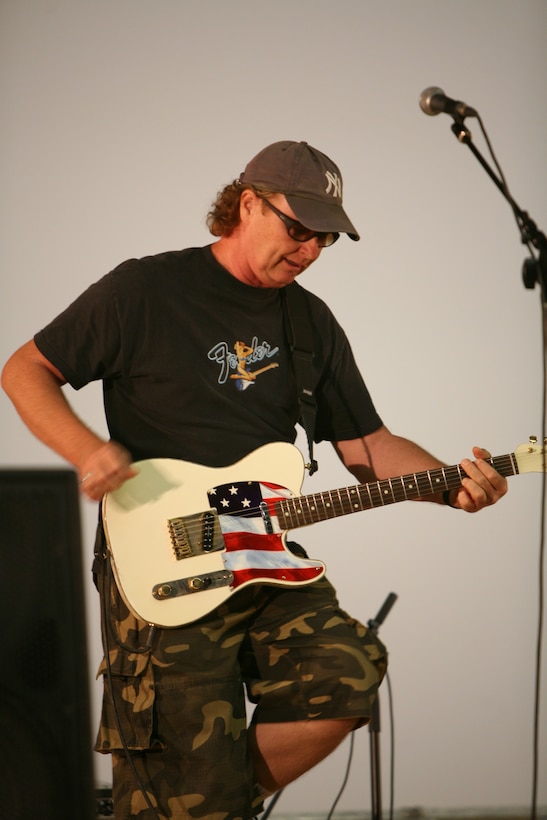 AL ASAD, Iraq - Art Holland, a guitarist with The Bootleggers, rocks out during one of songs the band played with Gina Notrica during a concert at the Al Asad base theater, July 3. Holland has participated in five concert tours to the Middle East.
