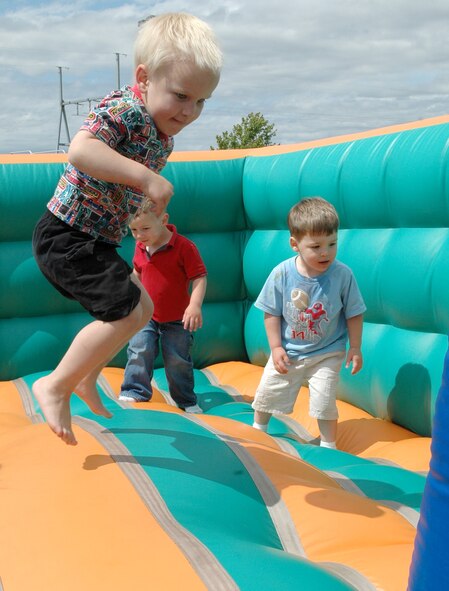 FAIRCHILD AIR FORCE BASE, Wash. -- Tevin Funderburg, 2, son of Tech Sgt. Joseph Funderburg, 92nd Logistics Readiness Squadron fuels technician, and Tara Funderburg, 336th Training Group secretary to the commander, soars high on the inflatable bouncer during the Child Development Center’s Watermelon Day event. Joining him in the fun are Ethan Newman, 2, son of Tech. Sgt. Jeremy Newman, 92nd Logistics Readiness Squadron fuels compliance supervisor, and Tech. Sgt. Mickie Newman, 92nd Operations Group information management NCOIC; and Skyler Mooney, 3, son of Senior Airman Christie Martin, 92nd Comptroller Squadron financial analyst. (U.S. Air Force photo/Airman 1st Class Kali L. Gradishar)