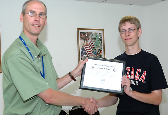 FAIRCHILD AIR FORCE BASE, Wash. -- Mr. Eric Quantock hands over a plaque to Cameron Moyer, one of the winners of the “Scholarship for Military Children.” Cameron graduated this year from Almira Coulee Hartline High School and received a $1,500 scholarship as well as a gift bag and a $25 commissary gift certificate. The scholarship was awarded based on grades, extra curricular activities and an essay themed, “If you could change one event in history, what would it be and why?” (U.S. Air Force photo/ Tech. Sgt. Larry W. Carpenter Jr.)