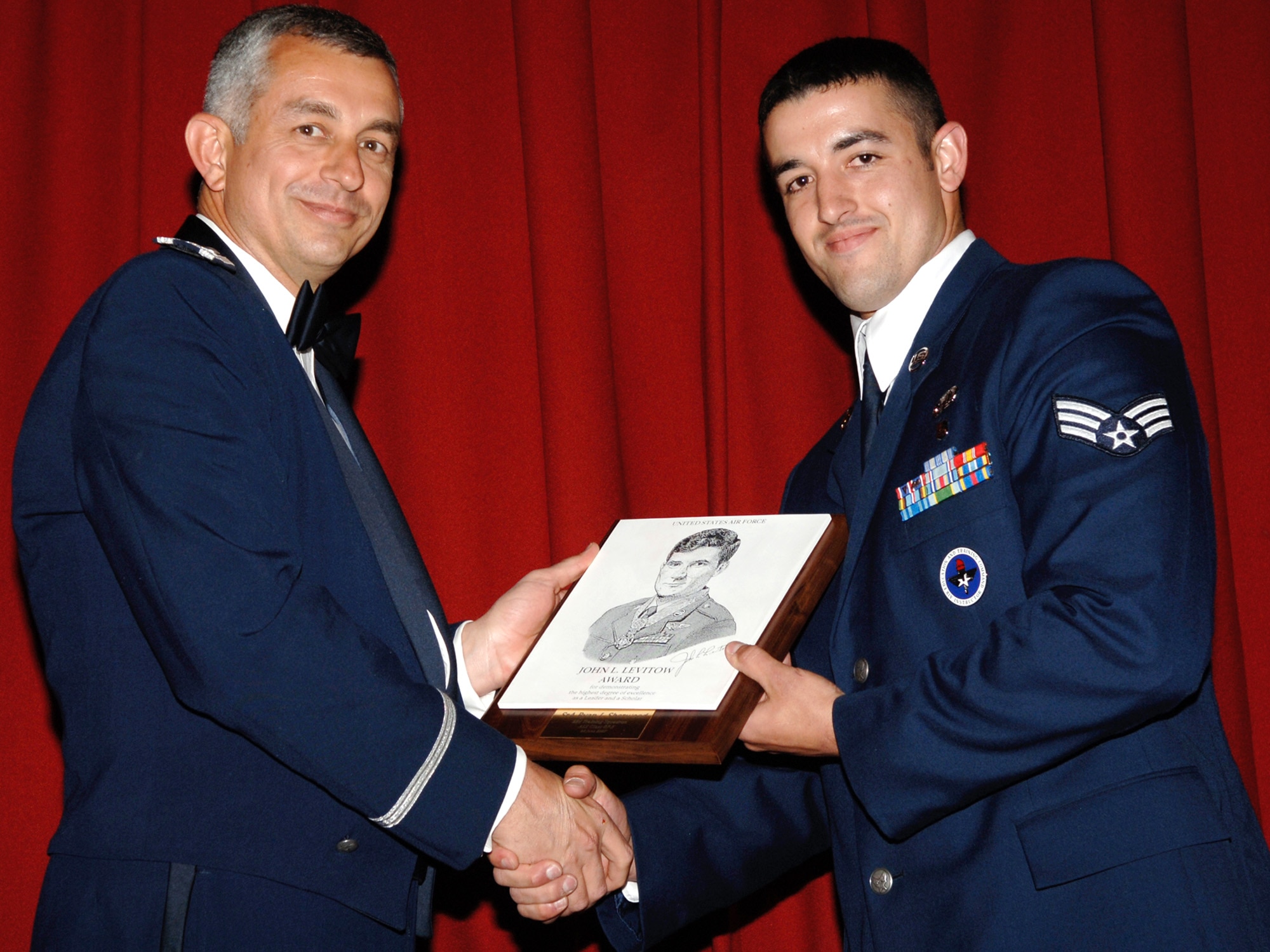 FAIRCHILD AIR FORCE BASE, Wash. -- Col. Roger Watkins, 92nd Air Refueling Wing vice commander, presents Senior Airman Ryan Sherwood with the John L. Levitow Award at the Airmen Leadership School graduation June 28. Airman Sherwood was presented with the award because of his support, interpersonal relationships and professionalism as an Airman. (U.S. Air Force photo/Airman 1st Class Nancy Hooks)