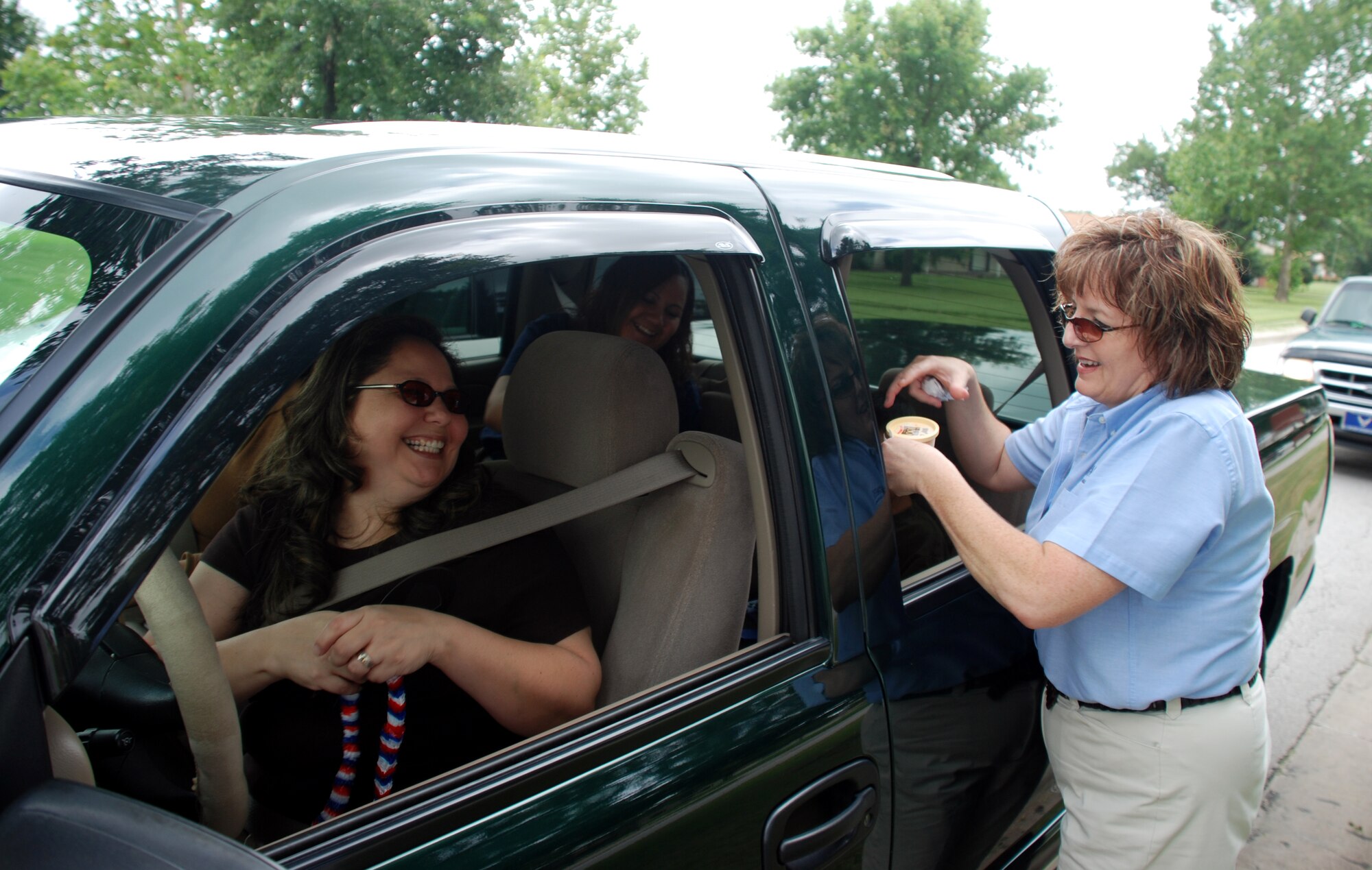 Shannon Gonzalez, a residential specialist with GMH Military Housing, hands out ice cream to Lisa Deleon and her family July 3 in Wherry housing. GMH handed out ice cream at all three housing areas as a Fourth of July treat. (U.S. Air Force photo/Airman 1st Class Jacob Corbin)