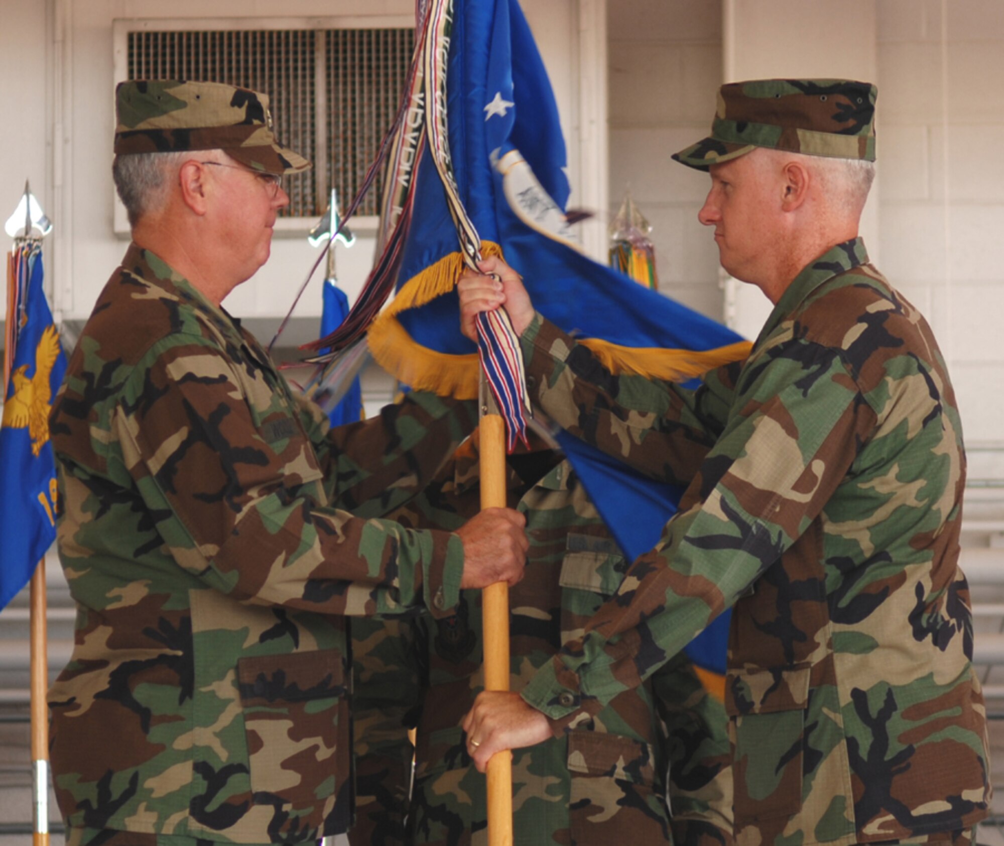 Col. Norm Brozenick Jr., former 1st Special Operations Wing commander, passes the 1st SOW guidon to Lt. Gen. Michael Wooley, Air Force Special Operations Command commander, during the change of command ceremony held Tuesday at Freedom Hangar. (U.S. Air Force photo by Senior Airman Andy Kin)