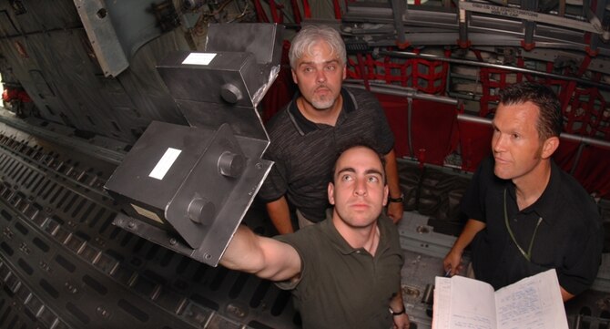 Jeremy Goldin, anti-skid engineer, holds a model of the anti-skid system while Ronald Crabtree (left), hydraulics specialist, and Todd Walker (right), engineer, all from Hill Air Force Base, Utah, look on. A modification team spent three days touring 21 C-130s for the development of a new anti-skid system projected to be installed in about 2010. (U.S Air Force photo by Airman 1st Class Steele Britton)