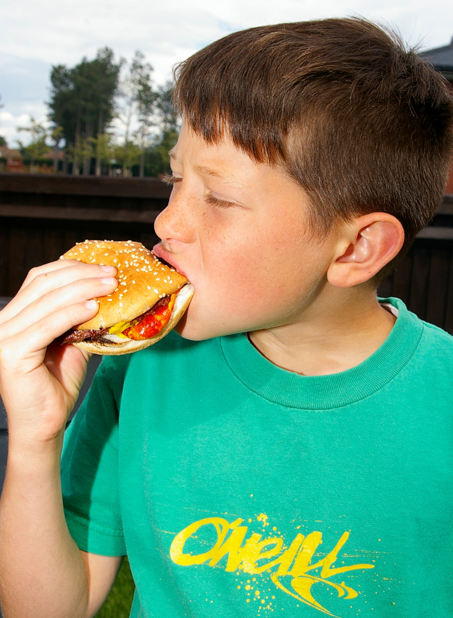 Colton Thomas, 10, takes time to enjoy his hamburger during the grand opening of Heritage Park July 3. Heritage Park is a children's play area, located by outdoor recreation, and is open 24 hours a day, seven days a week. (U.S. Air Force photo by Karen Abeyasekere)