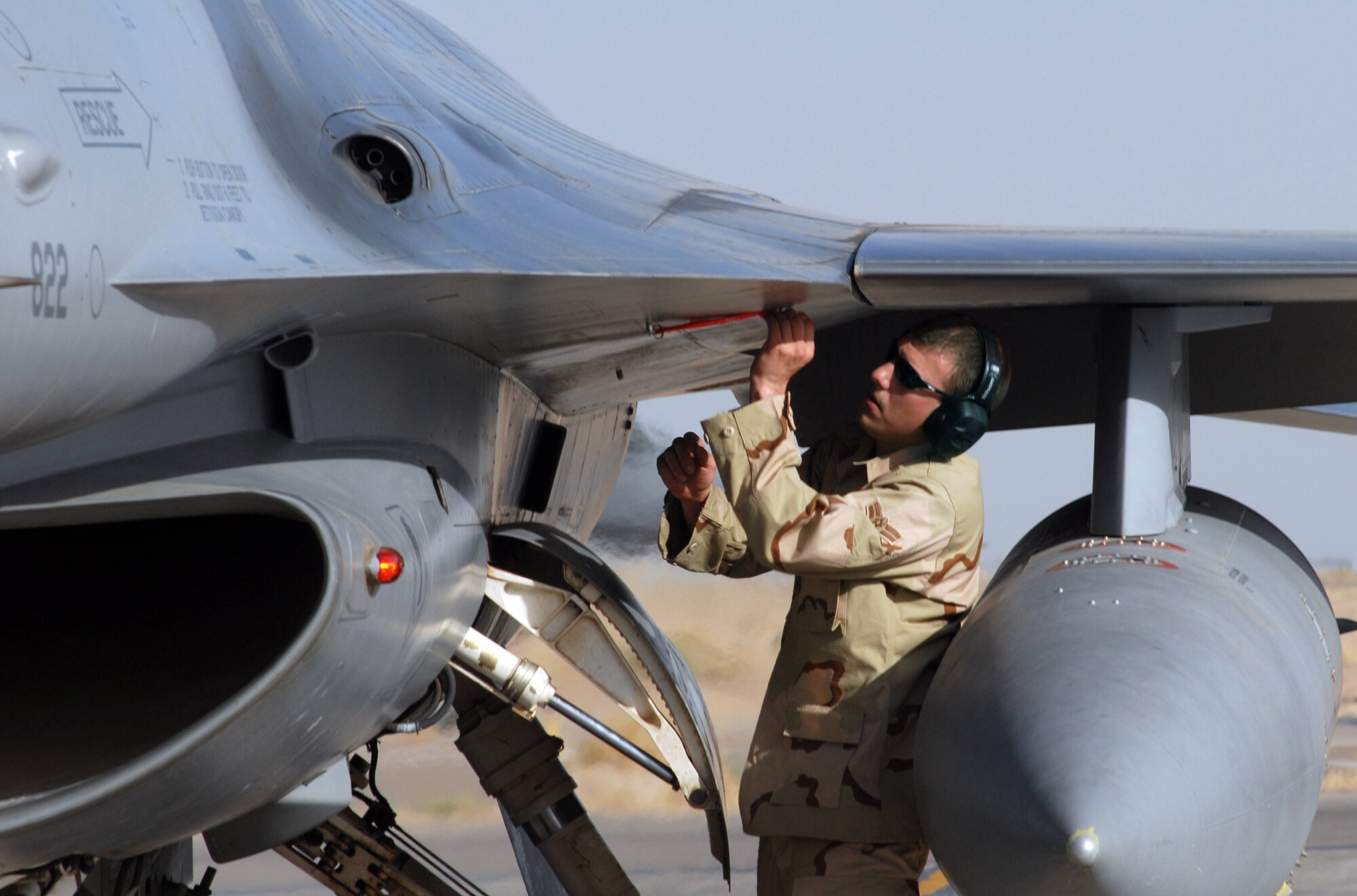 BALAD AIR BASE, Iraq -- Airman 1st Class Mark Drennen, a 332nd Expeditionary Aircraft Maintenance Squadron weapons load team member deployed from Misawa Air Base, Japan, removes the safety pin on an F-16 Fighting Falcon 20mm gun before a combat mission here June 27. The 332nd Air Expeditionary Wing has three F-16 squadrons, consisting of active duty Airmen, Air National Guardsmen and Air Force Reservists. The wing's F-16s are currently playing key close air support and show of force roles in Baqoubah for Operation Arrowhead Ripper. (photo by 1st Lt. Shannon Collins)
