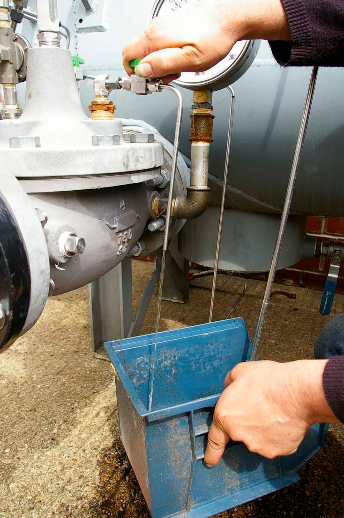 Recycled JP-8 runs clear as it comes out of the filtration system built by Paul Murfitt, 100th Civil engineer Squadron. When first being put into the filter, the fuel is a reddish color and runs between slightly yellow to clear once it has been filtered. (U.S. Air Force photo by Karen Abeyasekere)