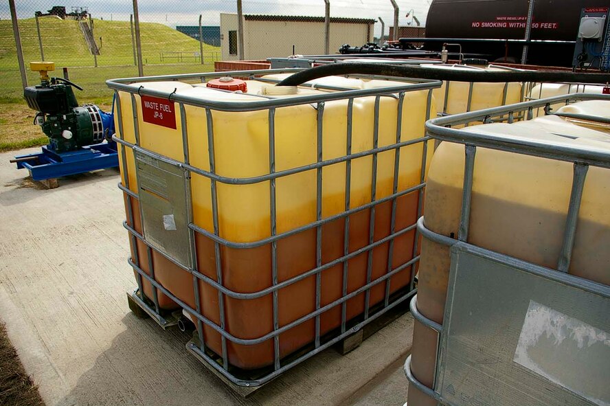 Contaminated JP-8 is stored in plastic containers before being put through the filtration equipment. The fuel will be filtered seven times before it can then be made into heating oil. The contaminated JP-8 starts off as a red color; after being filtered, it runs clear. Recycling the fuel so it can be used for heating oil will save the Air Force $4 per gallon. (U.S. Air Force photo by Karen Abeyasekere)