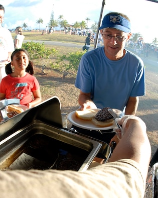 Michael Sachs, a retired Navy member, receives a hamburger while enjoying the activities at Andersen's Freedom Fest Tuesday. (U.S. Air Force Photo by Airman First Class Daniel Owen)