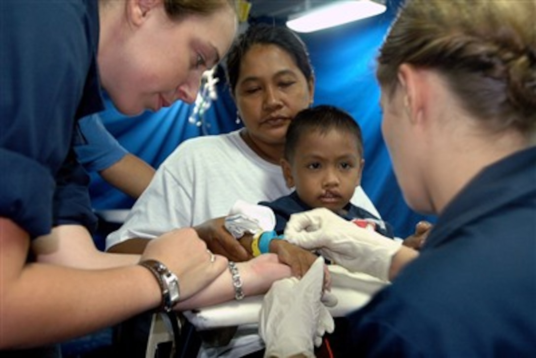 U.S. Navy Ensign Katherine Phillips, from Naval Medical Center San Diego, prepares to administer an IV to a Filipino child while Hospital Corpsman 3rd Class Barbara Linerooth comforts him before going into surgery to repair a cleft palate aboard the USS Peleliu (LHA 5) underway in the Philippine Sea on July 2, 2007.  Phillips and Linerooth are assisting local Filipinos as part of Exercise Pacific Partnership, a four-month humanitarian assistance mission to Southeast Asia and Oceania that includes specialized medical care and various construction and engineering projects.  