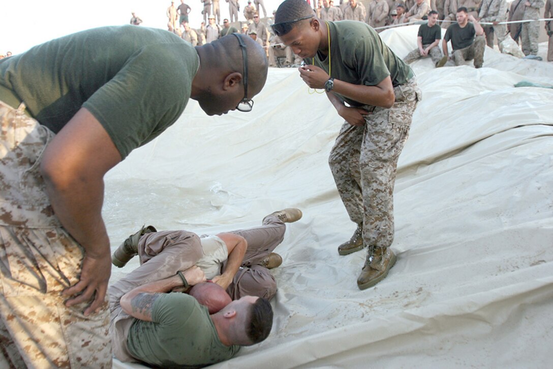 COMBAT OUTPOST RAWAH, IRAQ – Staff Sgt. Eugene A. Bristol (left) and Sgt. Jerome C. Ward (right), greenbelt instructors with 1st Light Armored Reconnaissance Battalion, Regimental Combat Team 2, watch competitors closely during the ground fighting competition on Highlander Day. The July 4th celebration was named after the battalion, the Highlanders, and is a standing tradition within the unit. Official Marine Corps Photo By Cpl. Ryan C. Heiser.