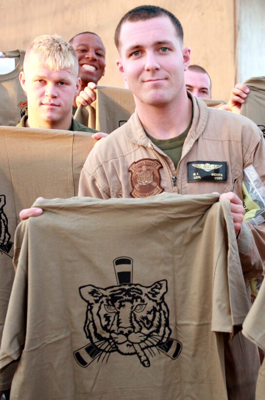 AL TAQADDUM, Iraq (July 4, 2007) ?   Lance Cpl. Michael T. Bedoya holds up a t-shirt here July 4.  The ?Flying Tigers? of Marine Medium Helicopter Squadron 262 were presented more than 200 screen printed T-shirts and 500 handwritten letters donated by citizens from Maine, Virginia and Connecticut during a ceremony. Bedoya is a crew chief with the squadron.