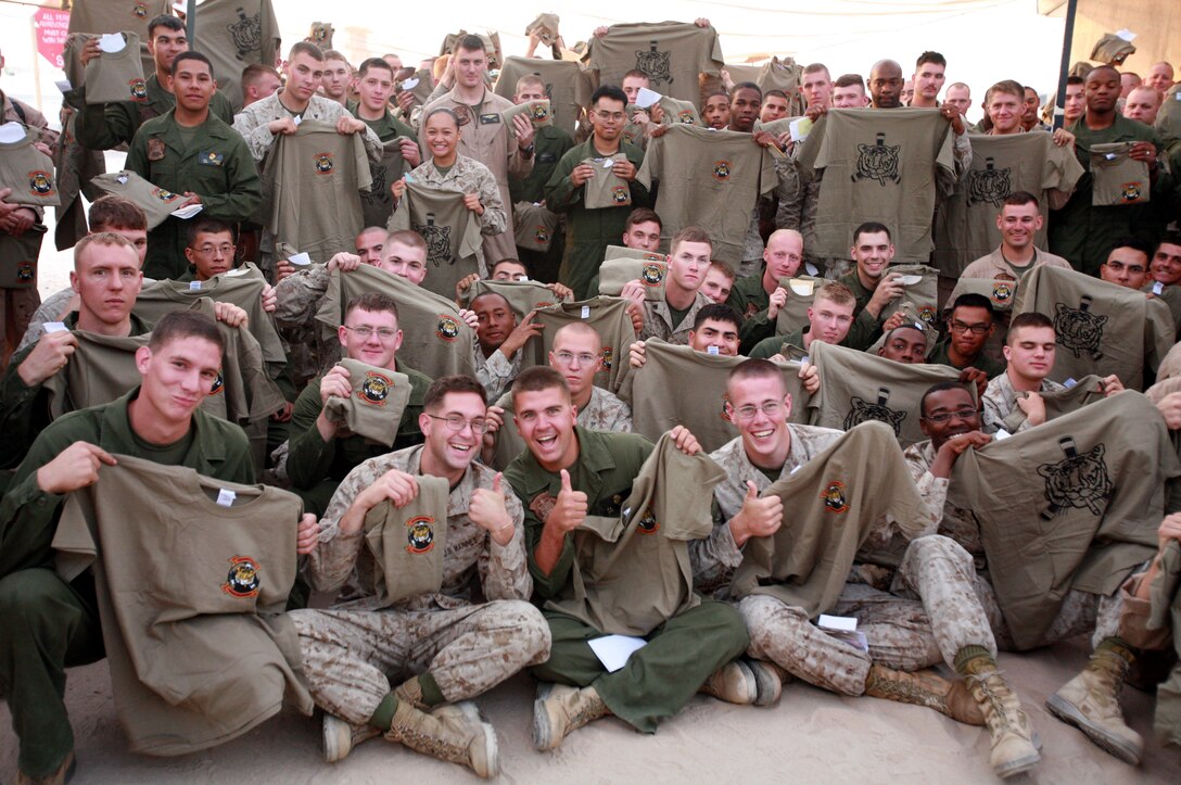 AL TAQADDUM, Iraq (July 4, 2007) ?   Marines hold up a t-shirts here July 4.  The ?Flying Tigers? of Marine Medium Helicopter Squadron 262 were presented more than 200 screen printed T-shirts and 500 handwritten letters donated by citizens from Maine, Virginia and Connecticut during a ceremony.