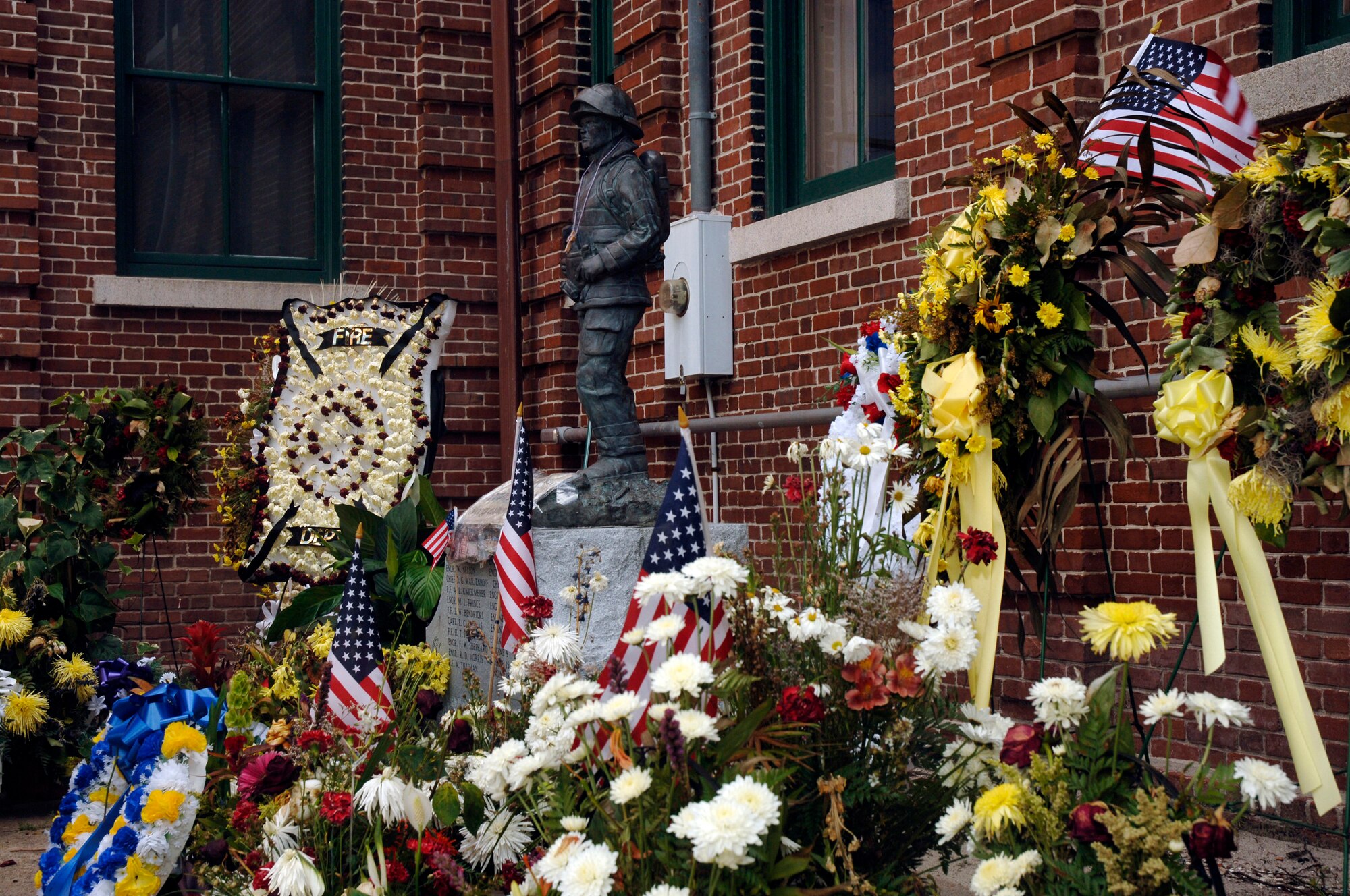 Wreaths of flowers and flags are placed by the local community around the firefighter statue at the Charleston Fire Department to show their support and respect for the nine fallen firefighters that lost their lives June 18.  (U.S. Air Force photo/ Staff Sgt. April Quintanilla)