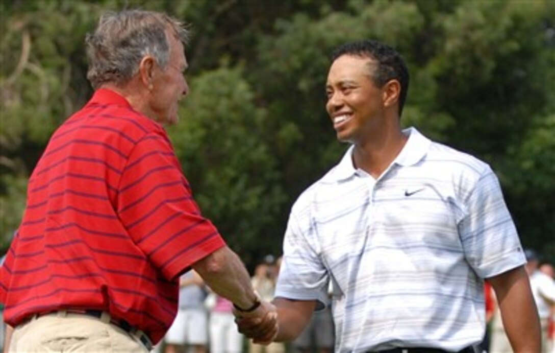 Former President George H.W. Bush greets Tiger Woods at the 16th hole during the inaugural Earl Woods Memorial Pro-Am Tournament, part of the AT&T National PGA Tour event, July 4, 2007, at the Congressional Country Club in Bethesda, Md. Woods donated 30,000 tickets to military personnel.