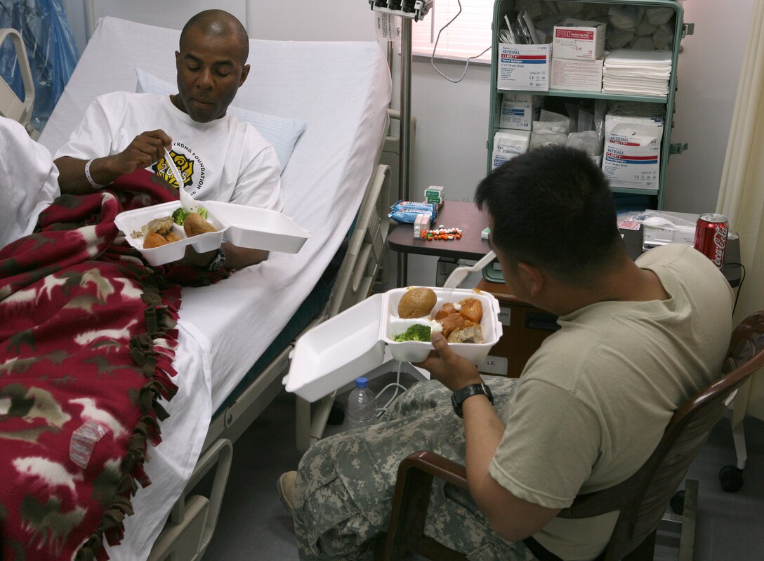 AL ASAD, Iraq - Army Spc. Chesley Barba, right, a fueler with Fox Company, 2nd Battalion, 504th Parachute Infantry Regiment, visits with his friend Army Sgt. Brian Price, a motor transportation driver with F Co., 2/504, at the 399th Combat Support Hospital, July 5. One of the advantages of the level III hospital is its ability to hold patients overnight or longer to allow them to recuperate.
