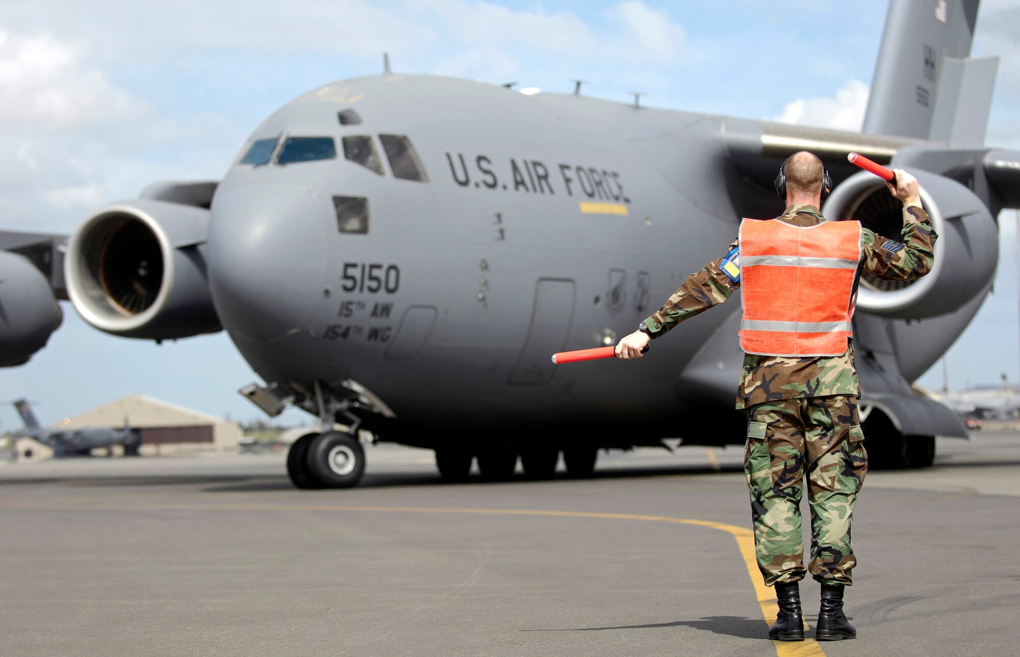 Tech. Sgt. Brad Sufka marshals a C-17 Globemaster III from its parking spot at Hickam Air Force Base, Hawaii, on June 28.  Sergeant Sufka is a crew chief from the 15th Aircraft Maintenance Squadron and is part of Hickam's Rodeo team. The team is practicing for the upcoming Air Mobility Command Rodeo at McChord AFB, Wash. (U.S. Air Force photo/Tech. Sgt. Shane A. Cuomo)
