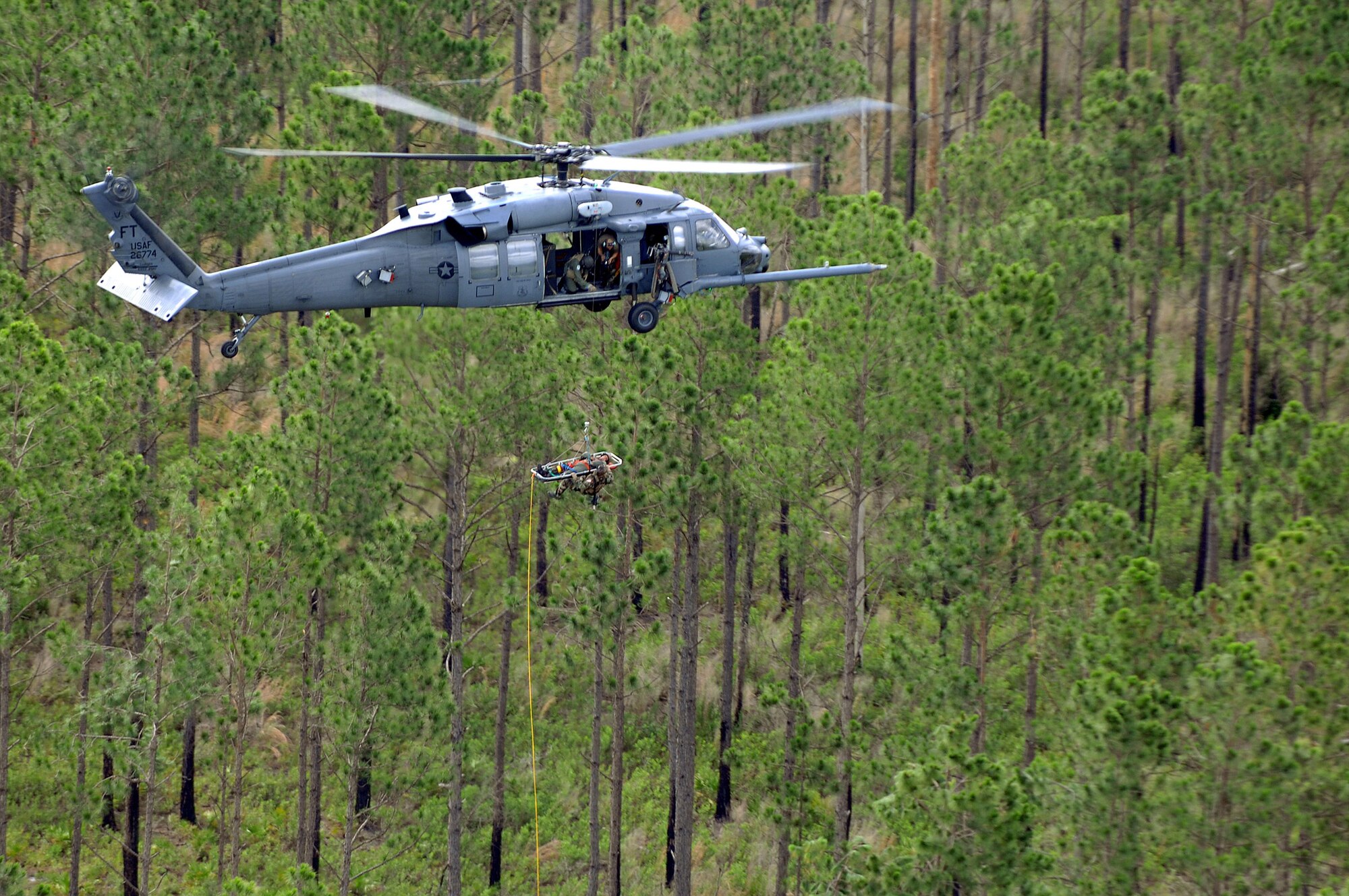 An HH-60 Pave Hawk crew hoists a "patient" and a pararescueman June 27 while being filmed by a video production team for the Air Force recruiting campaign, "Do Something Amazing."  The aircraft and crew are assigned to the 41st Rescue Squadron at Moody Air Force Base, Ga.  (U.S. Air Force photo/Master Sgt. Scott Reed) 