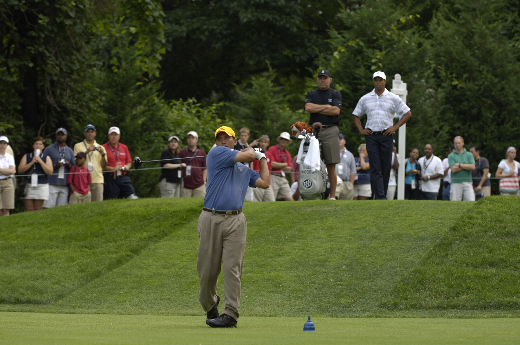 Tech. Sgt. Andy Amor, 316th Civil Engineer Squadron, Andrews Air Force Base, Md., tees off as professional golfer Tiger Woods and his caddie Steve Williams watch at Congressional Country Club in Bethesda, Md., July 4. Sergeant Amor was selected to represent the Air Force in the pro-am event before the start of the AT&T National Golf Tournament at Congressional. Tiger Woods was the event host as well as a contestant and spokesman. (U.S. Air Force photo by Senior Airman Dan DeCook)