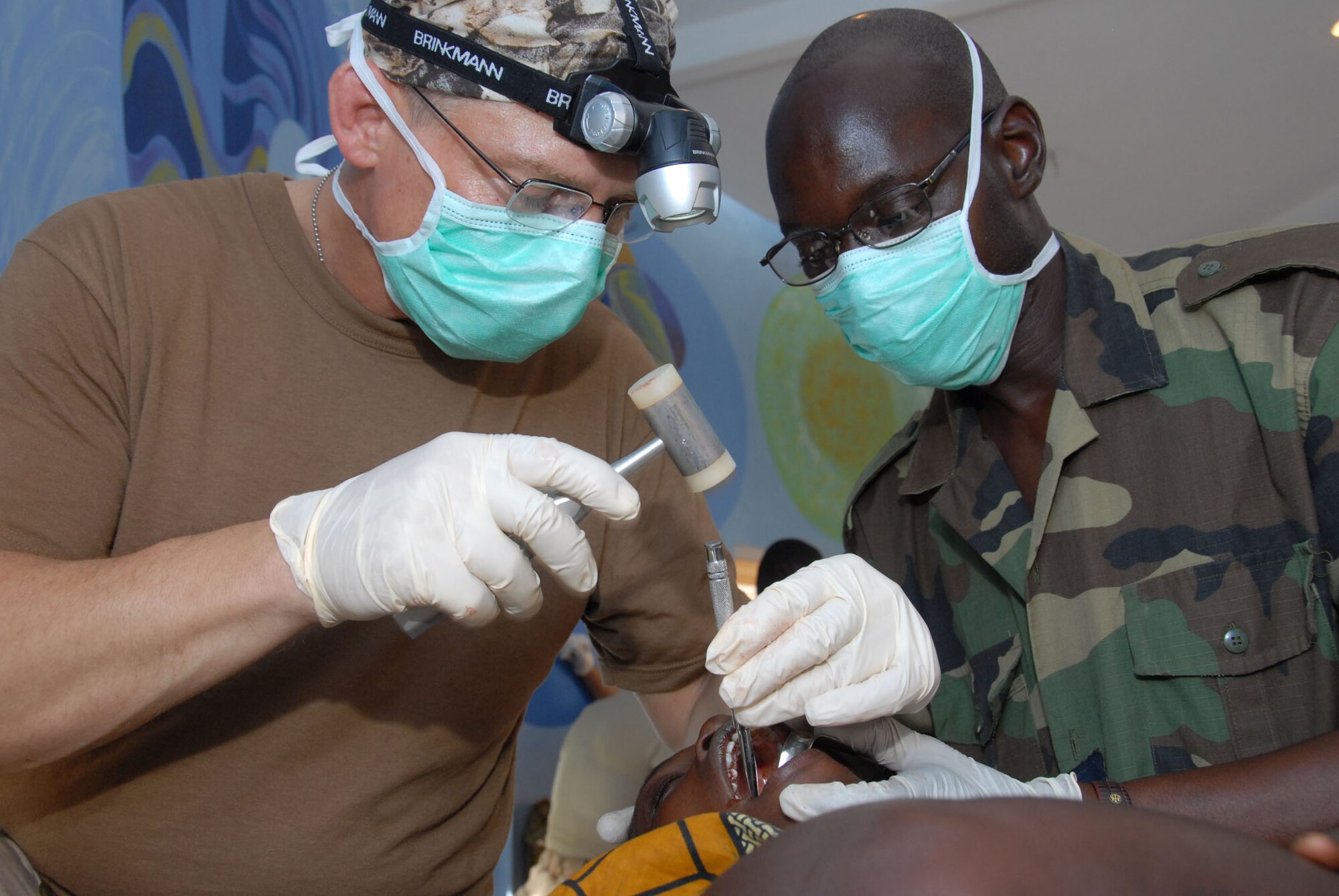 Lt. Col. (Dr.) Scott Sayre uses field denistry to remove bone in order to remove the tooth of a Senegalese patient during Shared Accord 07 in Linguere. Dr. Sayre is being assisted by Corp. Chief Idy Diarra, a surgical technician in the Senegalese Army. (U.S. Air Force photo/Master Sgt. Chance C. Babin)