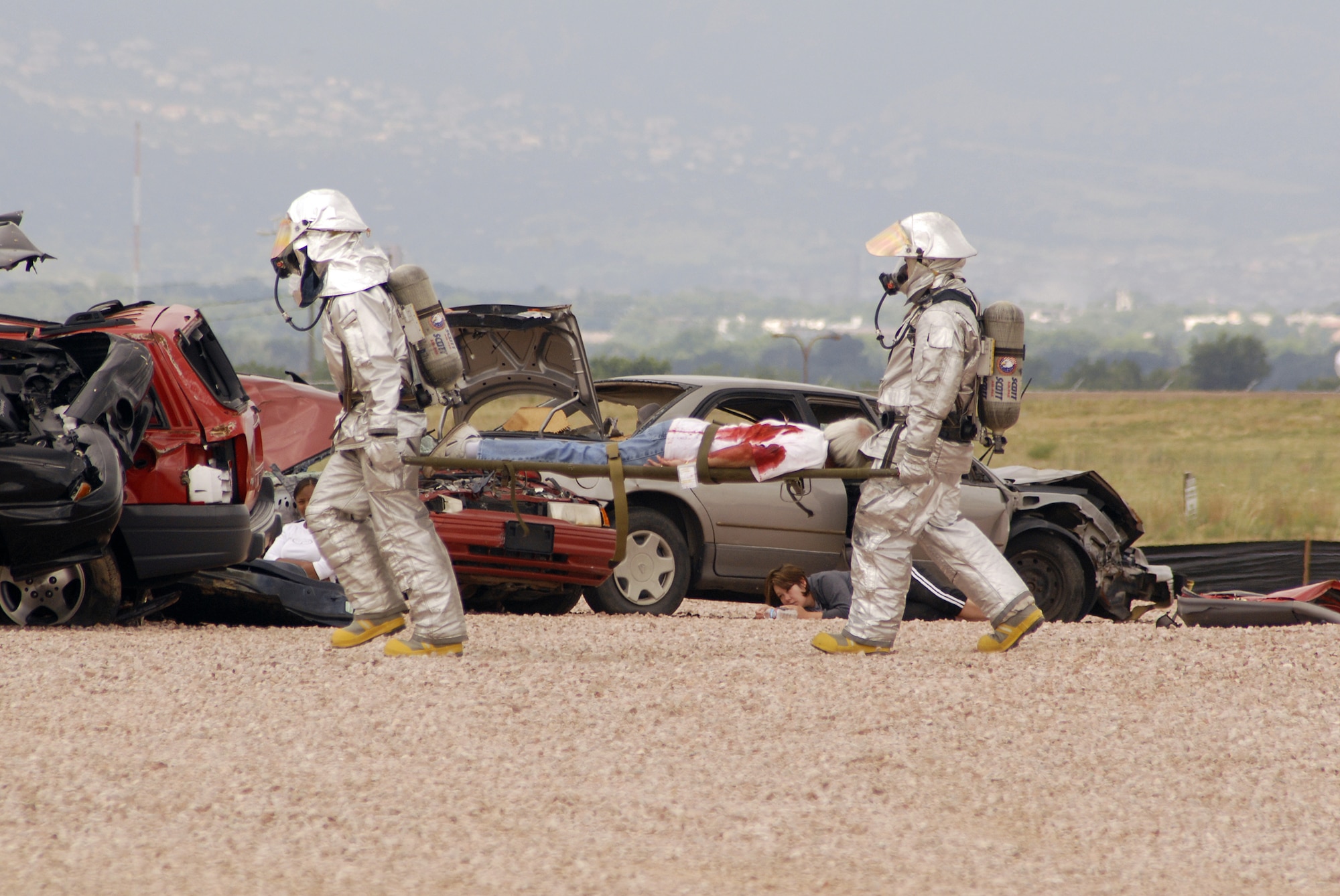 Peterson firefighters, donning hazardous material suits, carry casualties from the exercise scene. (U.S. Air Force photo by Larry Hulst)