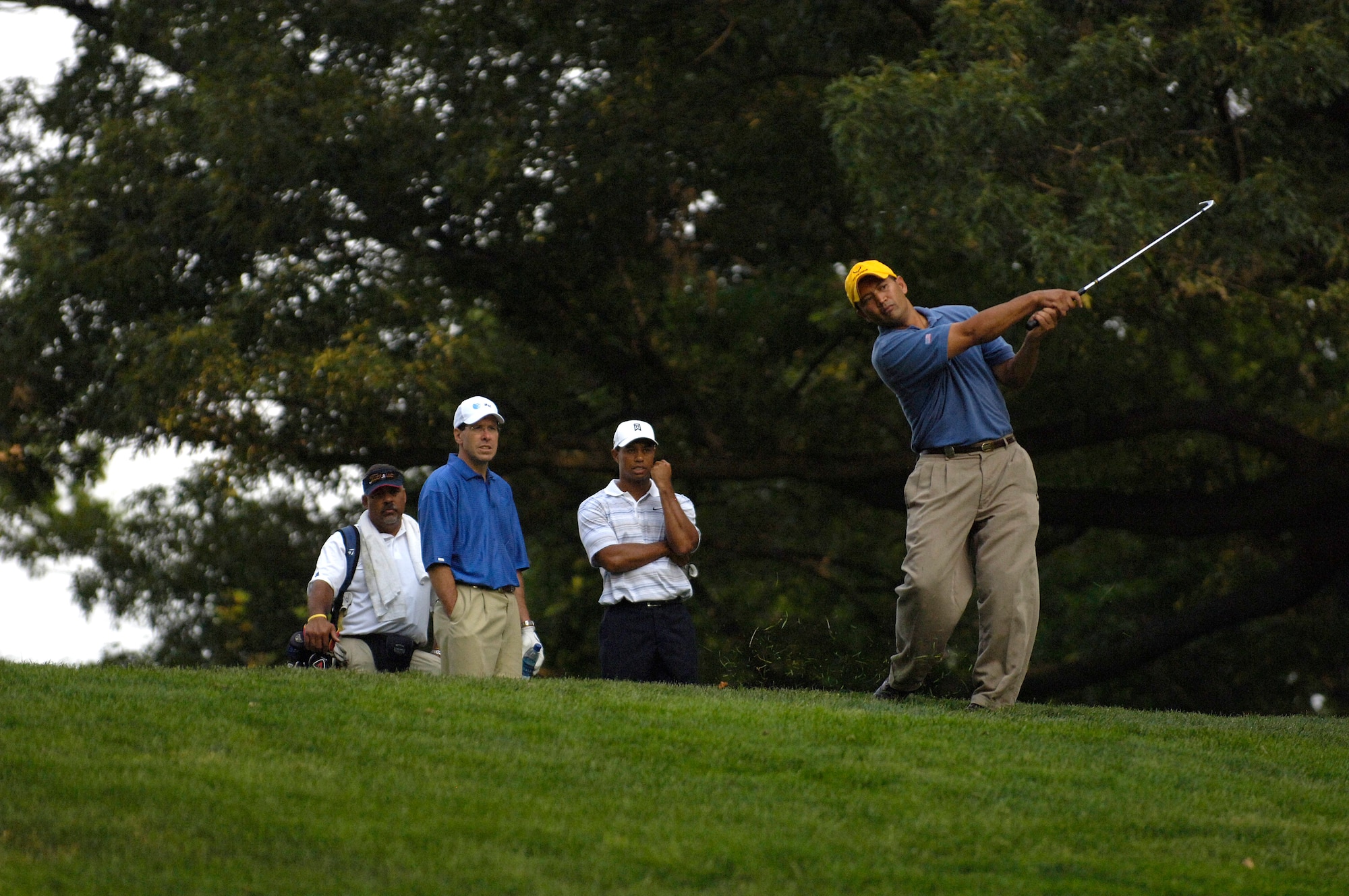 Tech. Sgt Andy Amor, 316th Civil Engineer Squadron, hits an approach shot as professional golfer Tiger Woods looks on. Sergeant Amor was selected to represent the Air Force in the Pro-Am event before the start of the AT&T National Golf Tournament at Congressional Country Club in Bethesda, Md., July 4. Tiger Woods is the event host as well as a contestant and spokes person. (U.S. Air Force photo by Senior Airman Dan DeCook)