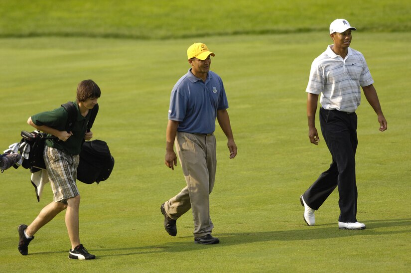 Tech. Sgt Andy Amor, 316th Civil Engineer Squadron, walks down a fair way with his caddy and son Drew Amor and professional golfer Tiger Woods. Sergeant Amor was selected to represent the Air Force at a Pro-Am event before the start of the AT&T National Golf Tournament at Congressional Country Club in Bethesda, Md. July 4. Tiger Woods is the event host as well as a contestant and spokes person. (U.S. Air Force photo by Senior Airman Dan DeCook)