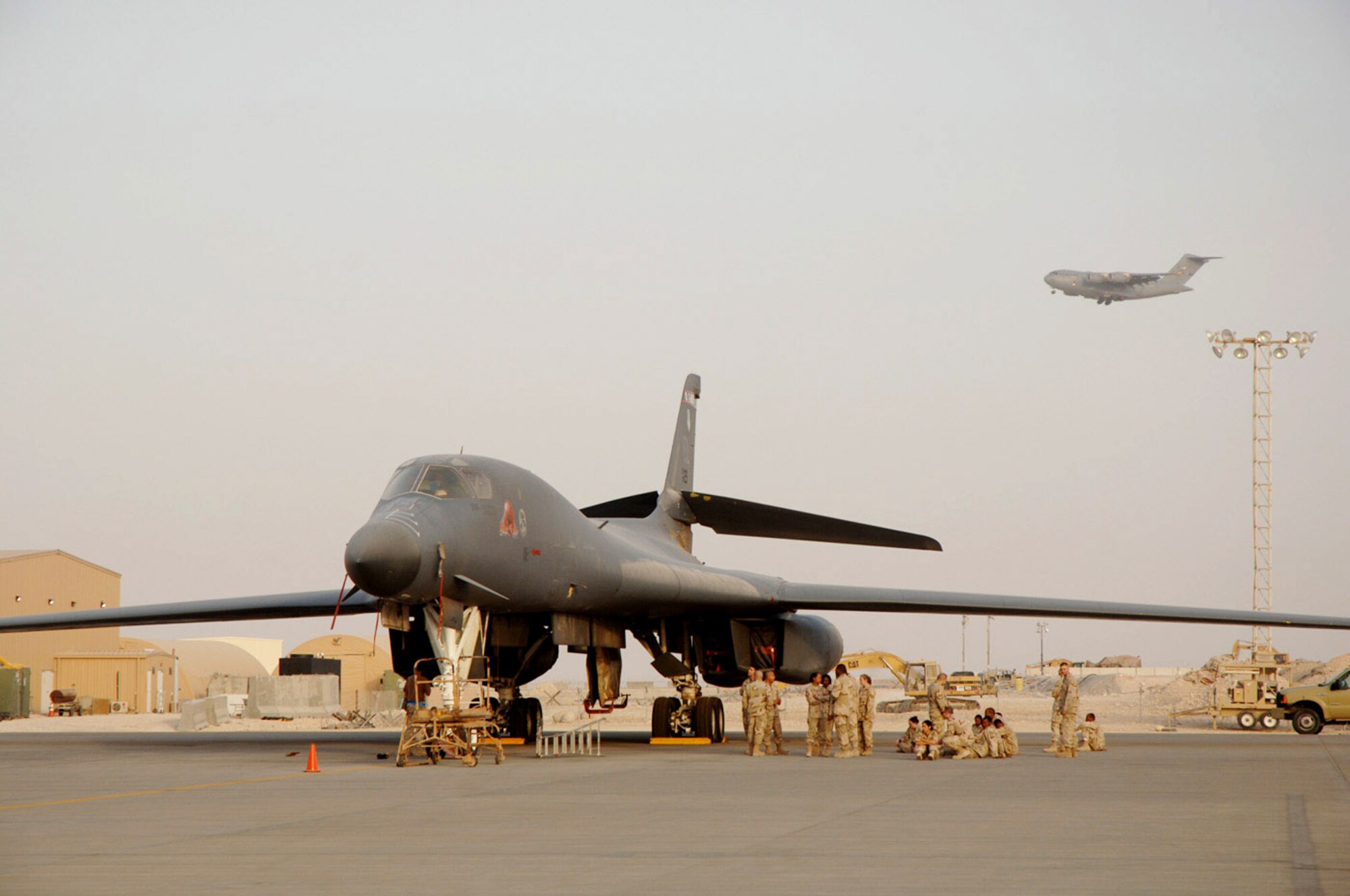 Maintainers ensure this B-1B Lancer is ready to go as a C-17 Globemaster III prepares to land at a forward deployed location in Southwest Asia July 1.  B-1s provide close-air support for both Operation Enduring Freedom and Operation Iraqi Freedom.  (U.S. Air Force photo/Master Sgt. Ken Stephens)