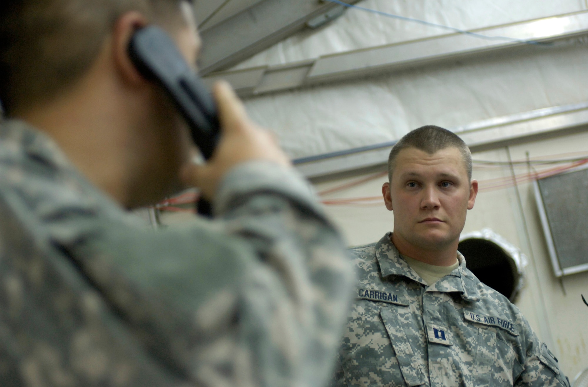 Capt. Kevin Carrigan (rear), an air liaison officer, listens as Tech. Sgt. Mike Cmelik, a joint terminal attack controller, directs a B-1 Lancer to drop bombs on an explosives-laden roadway south of Baghdad.  Captain Carrigan and Sergeant Cmelik, both deployed with the 15th Expeditionary Air Support Operations Squadron, are assigned to provide support to the U.S. Army's 2nd Brigade combat team at Forward Operating Base Kalsu, Iraq,.  (U.S. Air Force photo/Master Sgt. Jim Varhegyi) 