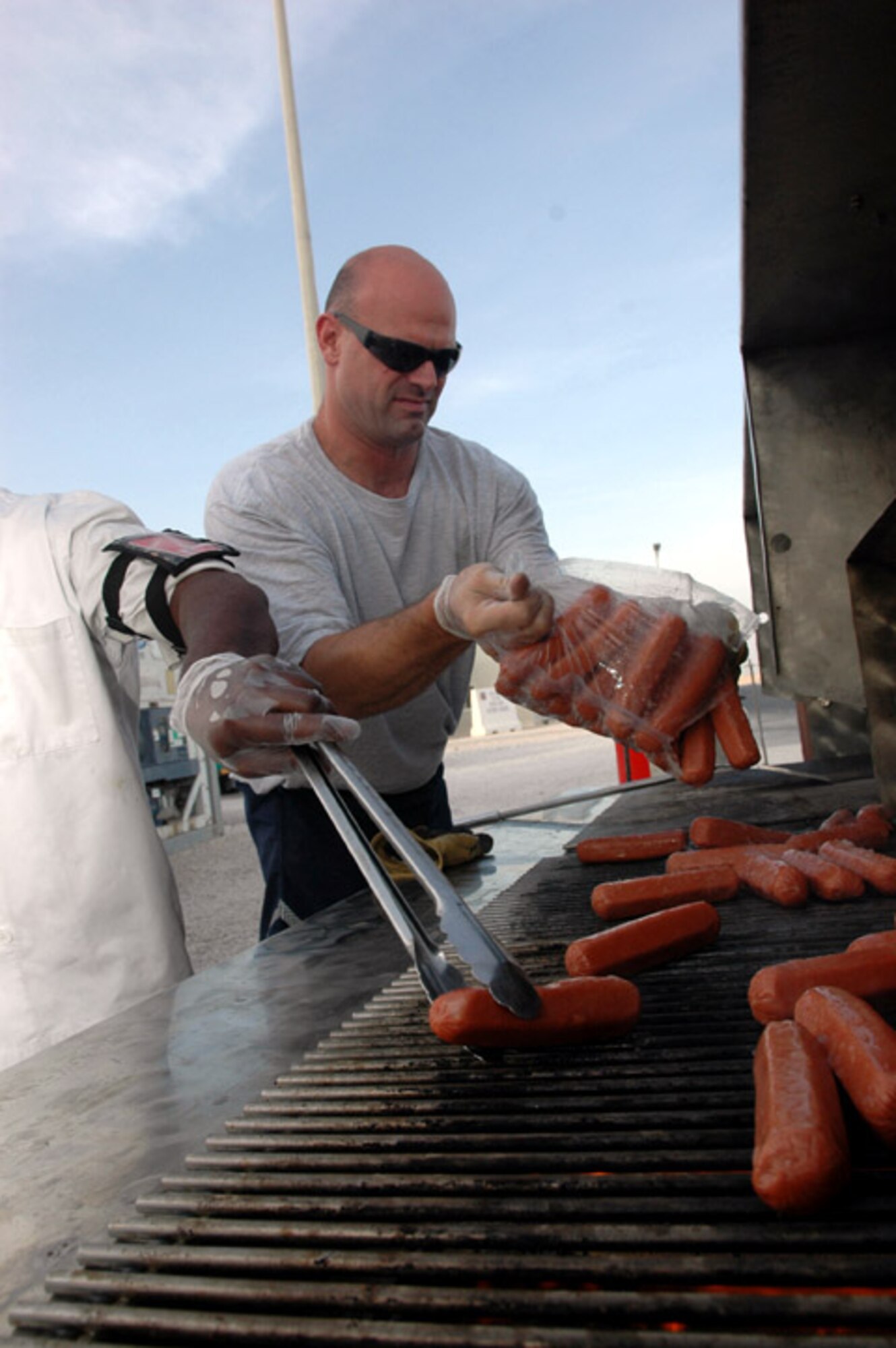 Staff Sgt. John Cooper cooks hot dogs for a Fourth of July celebration at a deployed location in Southwest Asia. Sergeant Cooper is assigned to the 379th Expeditionary Services Squadron.  (U.S. Air Force photo/Senior Airman Clark Staehle)