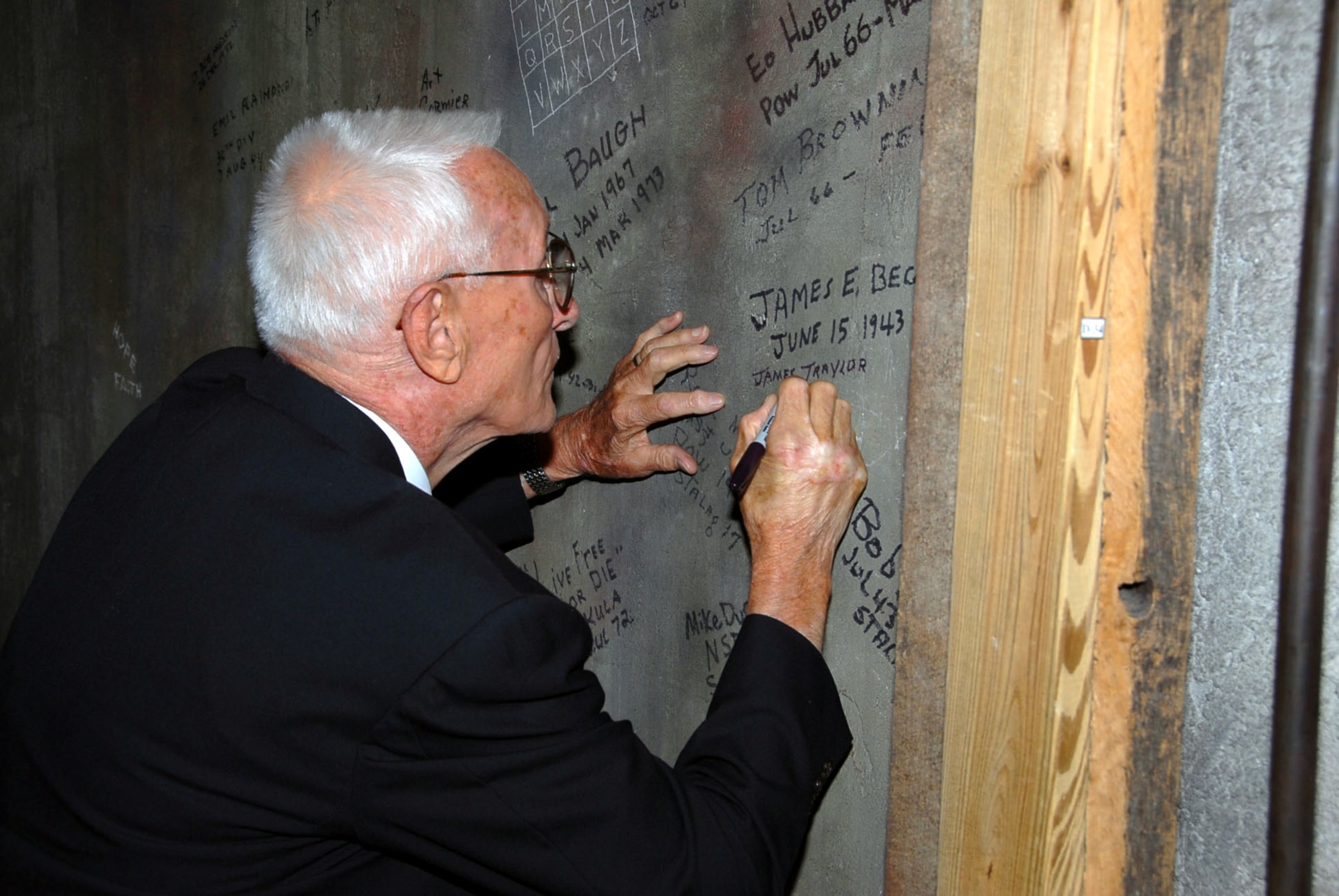 Retired Master Sgt. James Traylor signs a wall July 3 in the POW exhibit at the Enlisted Heritage Hall museum at Maxwell-Gunter Air Force Base, Ala., after being inducted into the museum's hall of fame. Mr. Traylor is from Alabama and served in World War II, where he was a prisoner of war at the Stalag 17 camp, as well as Vietnam.  (U.S. Air Force photo)