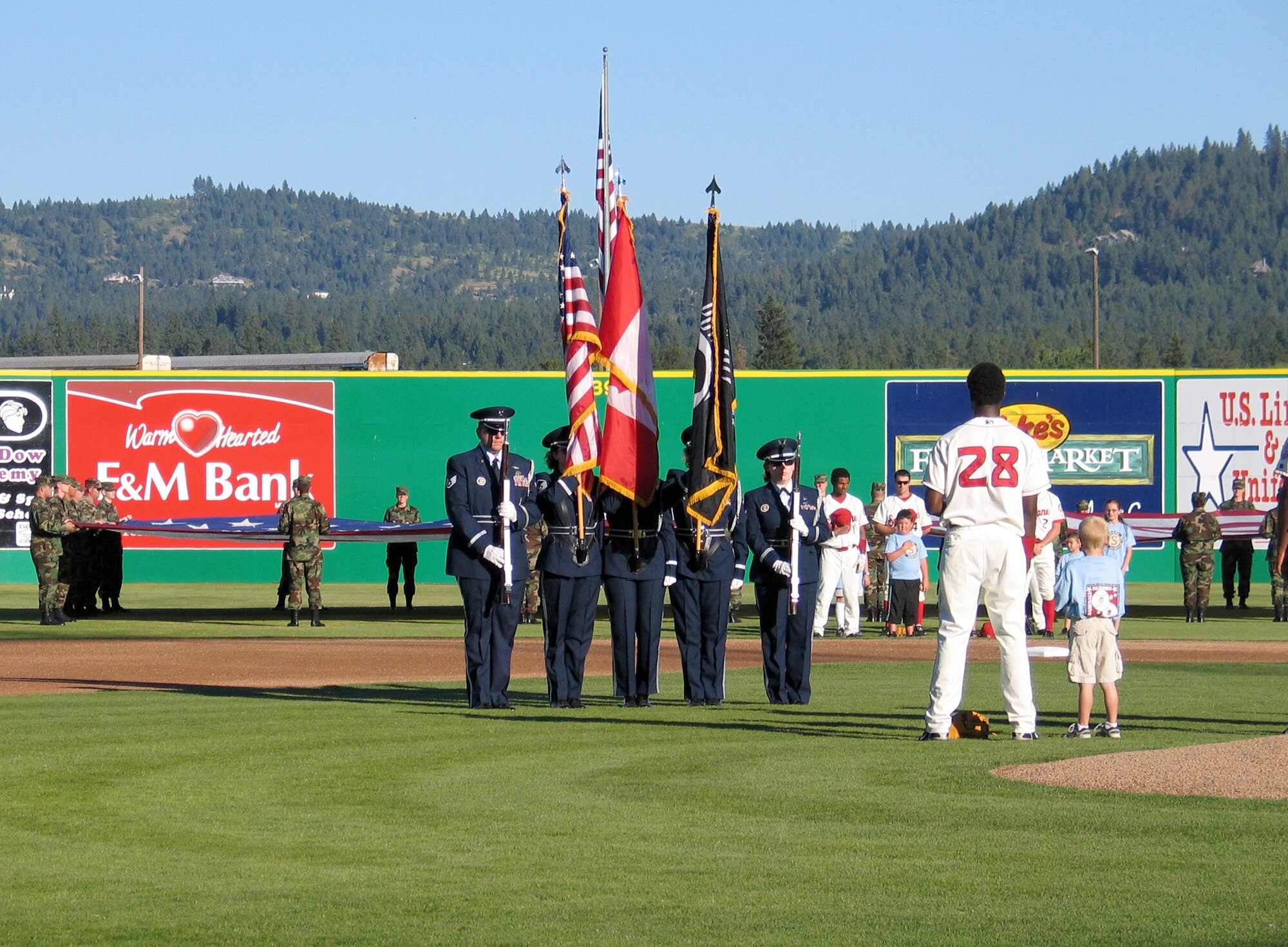 FAIRCHILD AIR FORCE BASE, Wash. – Fairchild Honor Guard members post the colors during the National Anthem on the Avista Stadium field in Spokane during a patriotic pre-game ceremony July 4. Behind the Honor Guard, thirty active-duty Air Force members from Fairchild hold an American flag as Spokane Indians baseball players honor the flag and anthem. More than 7,000 baseball fans attended the game and ceremony. (U.S. Air Force photo/ Staff Sgt. Connie L. Bias) 
