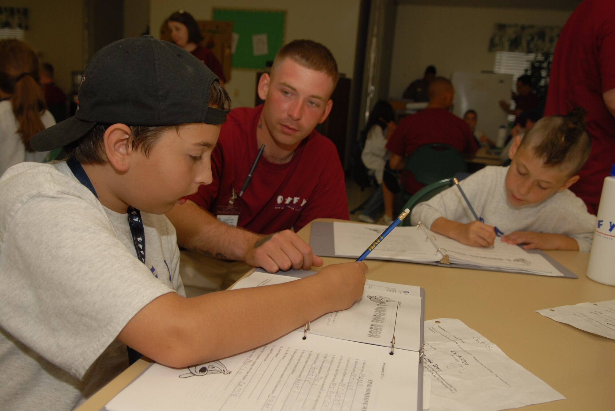 Army Pvt. Jeff Quinn (center) helps Chris Mutka (left) and Keegan Pace (right) fill out a worksheet during the DEFY program. (U.S. Air Force Photo by Airman 1st Class Kamaile Chan)