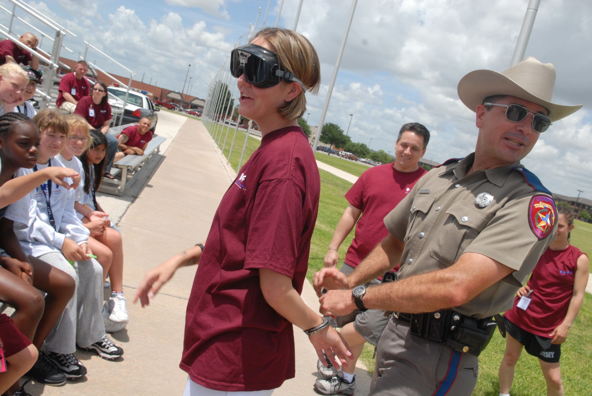 Texas Department of Public Safety Trooper Shawn Baxter puts Staff Sgt. Stacie Myers in handcuffs during a demonstration on the dangers of drinking and driving. In addition to being a volunteer with the Drug Education for Youth program, Sergeant Myers is the president of Airmen Against Drunk Driving. (U.S. Air Force Photo by Airman 1st Class Kamaile Chan)