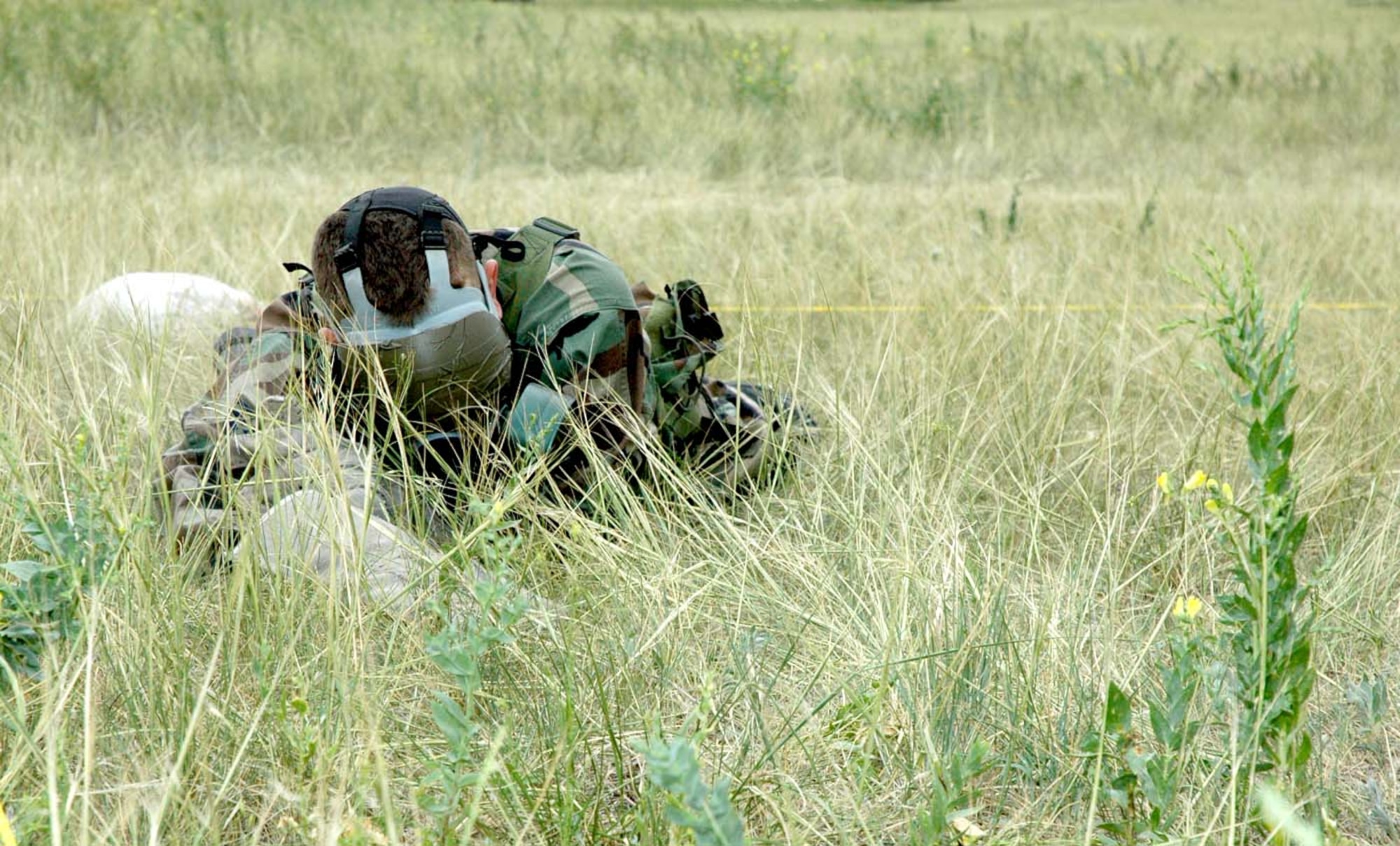 Senior Airman Daren Marshall, 790th Missile Security Forces Squadron, searches blindly for an ammo box in the surrounding area. Members of the team were required to low crawl while patrolling the roped-off section (Photo by Airman 1st Class Daryl Knee).