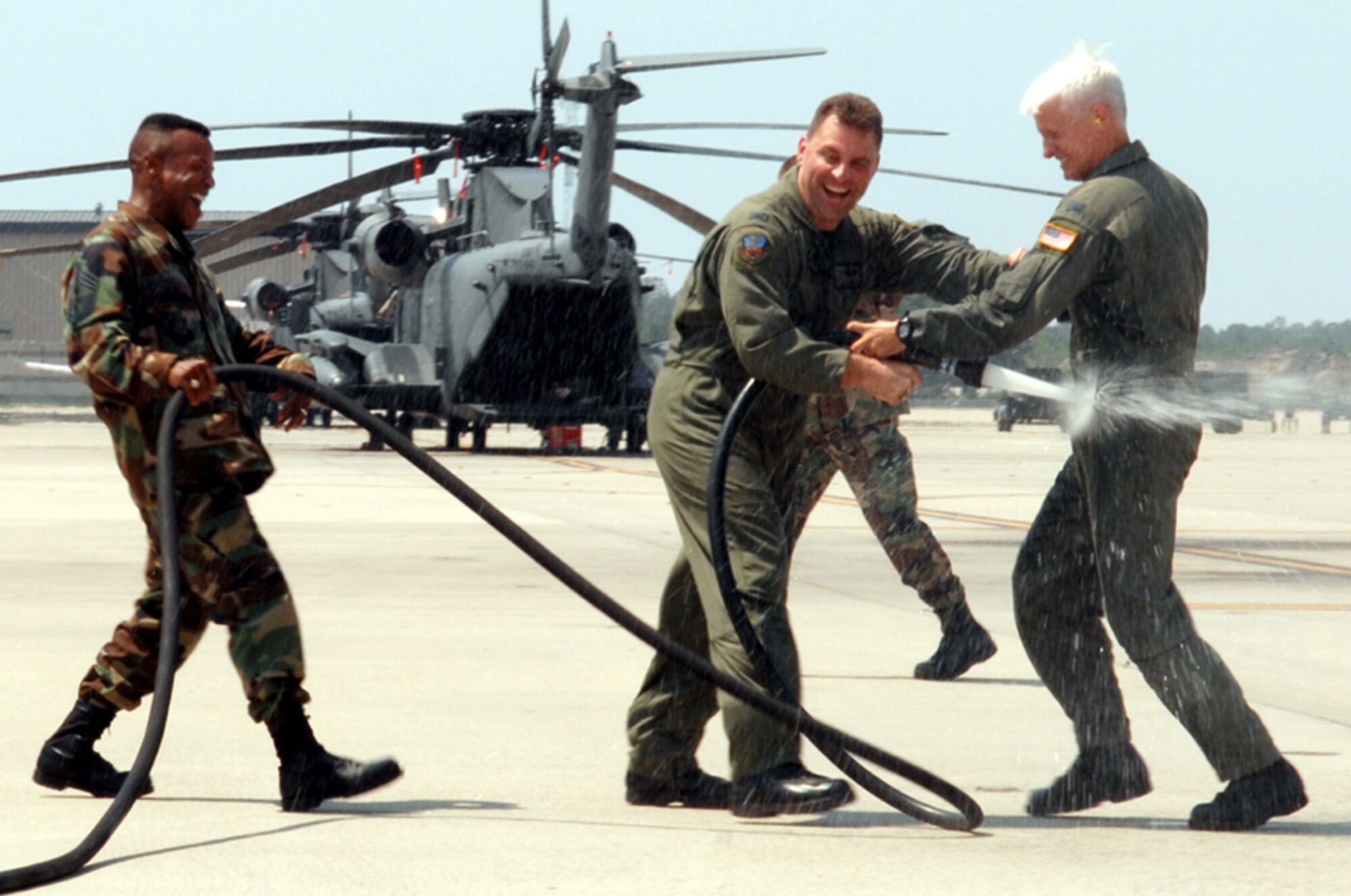 Chief Master Sgt. Jeffrey Richardson, 1st Special Operations Wing command chief, and Col. Timothy Leahy, 1st SOW vice commander, spray down Col. Norm Brozenick Jr., previous 1st SOW commander, after his fini flight June 28. (U.S. Air Force photo/Senior Airman Andy Kin)