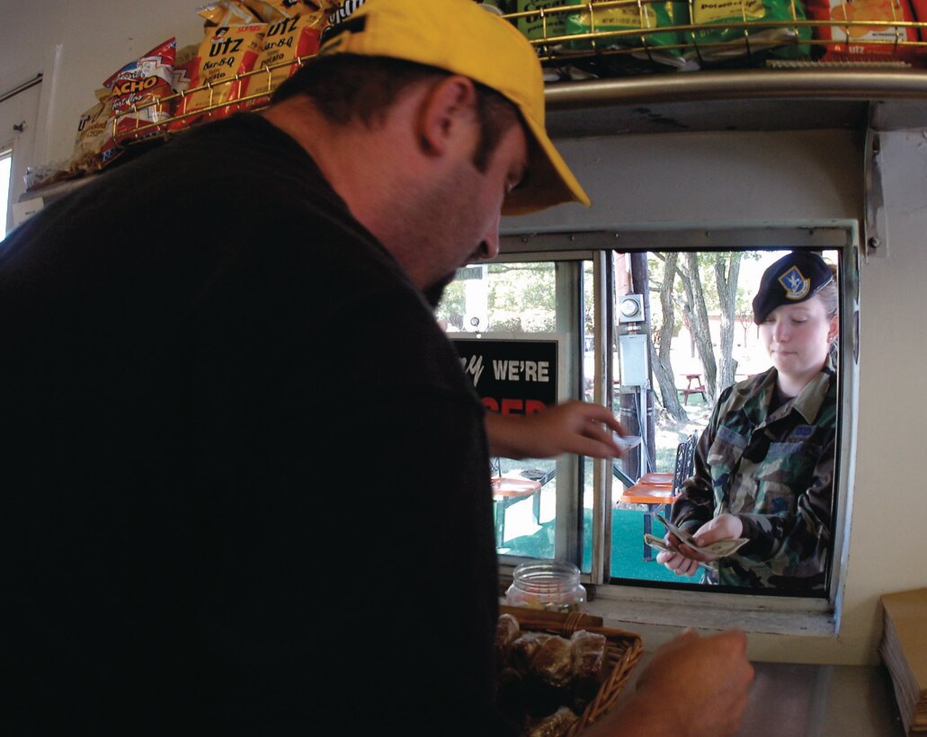 Gordon Coder, a Loretta's Barbecue employee, receives payment from Senior Airman M. Raley, 459th Security Forces Squadron fire team member. Loretta's Barbecue is located on East Perimeter Road and Fetchet Avenue. (Photo by Bobby Jones)