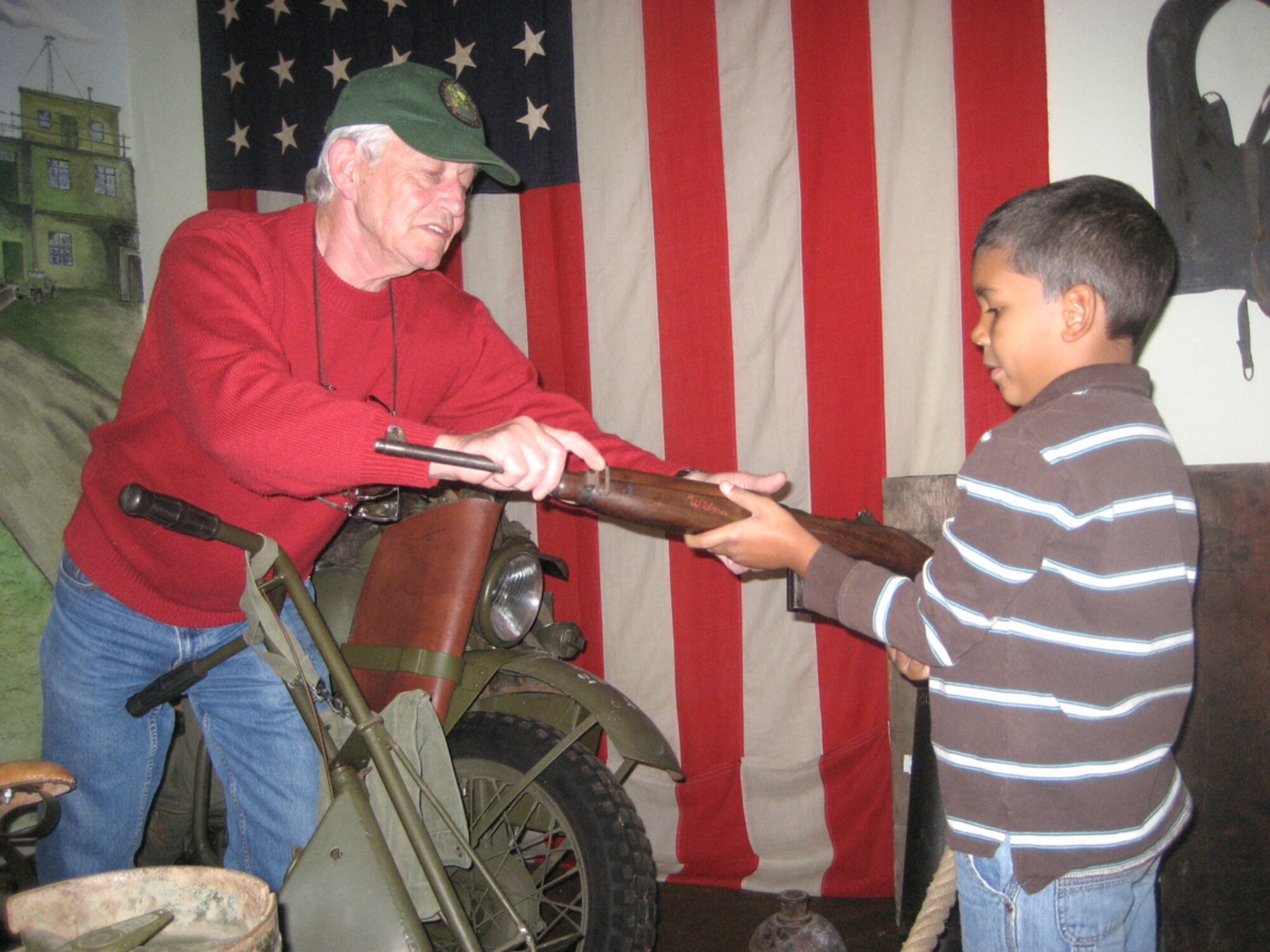 SPANGDAHLEM AIR BASE GERMANY -- Roger Feller, who owns and operates the 385th Bomb Group Museum in Perle, Luxembourg, shows Nolan Raybon, 7, son of Staff Sgt. Terrence Raybon, 52nd Mission Support Squadron, an M-1 Carbine rifle during a visit July 5, 2007. Several people from Spangdahlem AB visited the museum as part of a trip sponsored by the European Military History Group that day. (U.S. Air Force photo/Staff Sgt. Andrea Knudson)