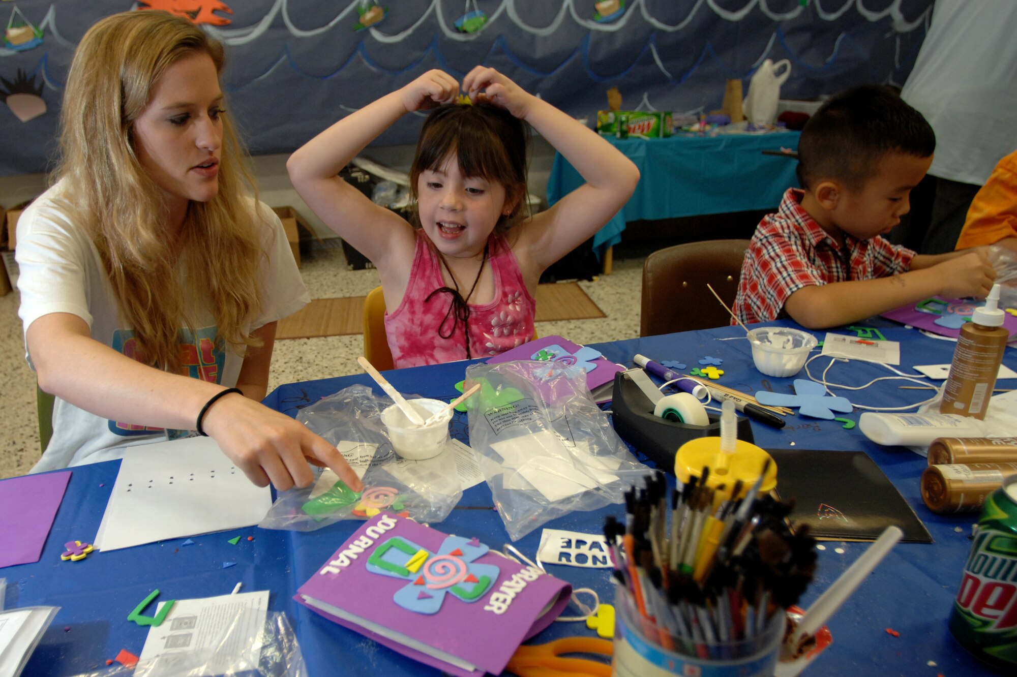 Lauren Johnston, 31st Fighter Wing chapel protestant religious education coordinator, helps children create Bible journals during an arts and crafts portion of Vacation Bible School. (U.S. Air Force photo by Airman 1st Class Nathan Doza)