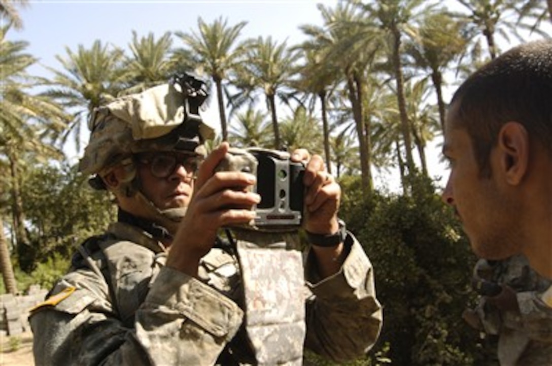 A U.S. Army soldier with Alpha Company, 1st Battalion, 30th Infantry Regiment uses handheld interagency identity detection equipment to scan a man's retina in Arab Jabour, southern Baghdad, Iraq, on June 29, 2007.  