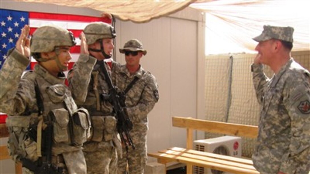 U.S. Army Pfc. Richard Fletcher and Spc. Christopher Watson raise their right hands and cite the oath of re-enlistment at Forward Operating Base Warhorse, Iraq, July 7, 2007.  Army Gen. David Petraeus (right), commanding general, Multi-National Forces-Iraq, re-enlisted eight soldiers from 1st  Battalion, 23th Infantry Regiment, Fort Lewis, Wash. Spc. Marcus Cleary, Pfc. Brandon Tiago, Sgt. Douglas Wagner, Spc. Matthew L. Phillips, Spc. Ryan Werts, and Spc. Demetris Gilbert also re-enlisted. 
