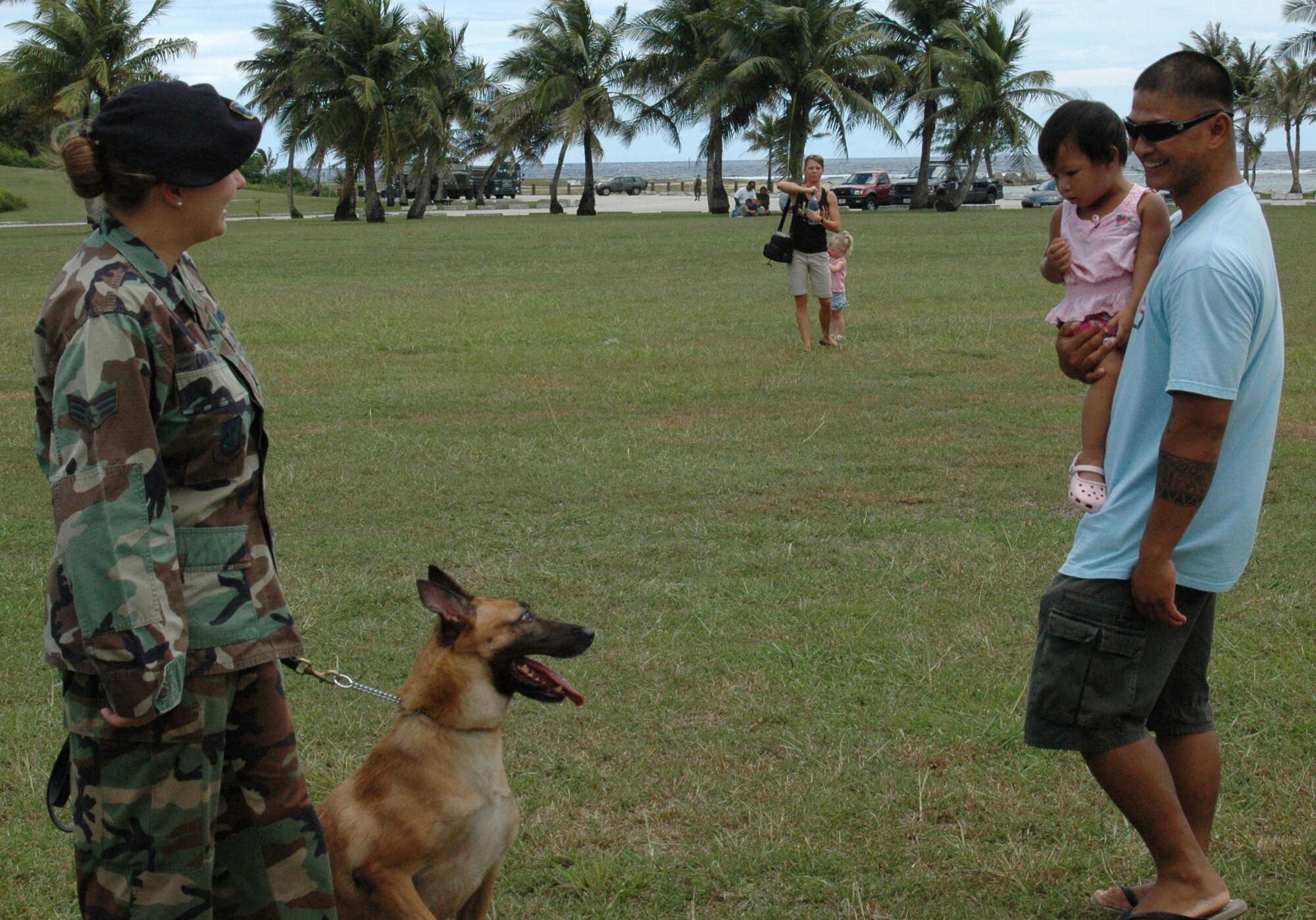 Senior Airman Darlene Donoho, 36th Security Forces Squadron, shows her dog to Kenneth and Cloey Ray TedTaoTao during the pre-Liberation Day military expo at Asan Beach July 7. Several units from Andersen were represented to help familiarize the local community with Andersen's mission. (U.S. Air Force photo by Capt. Joel Stark)