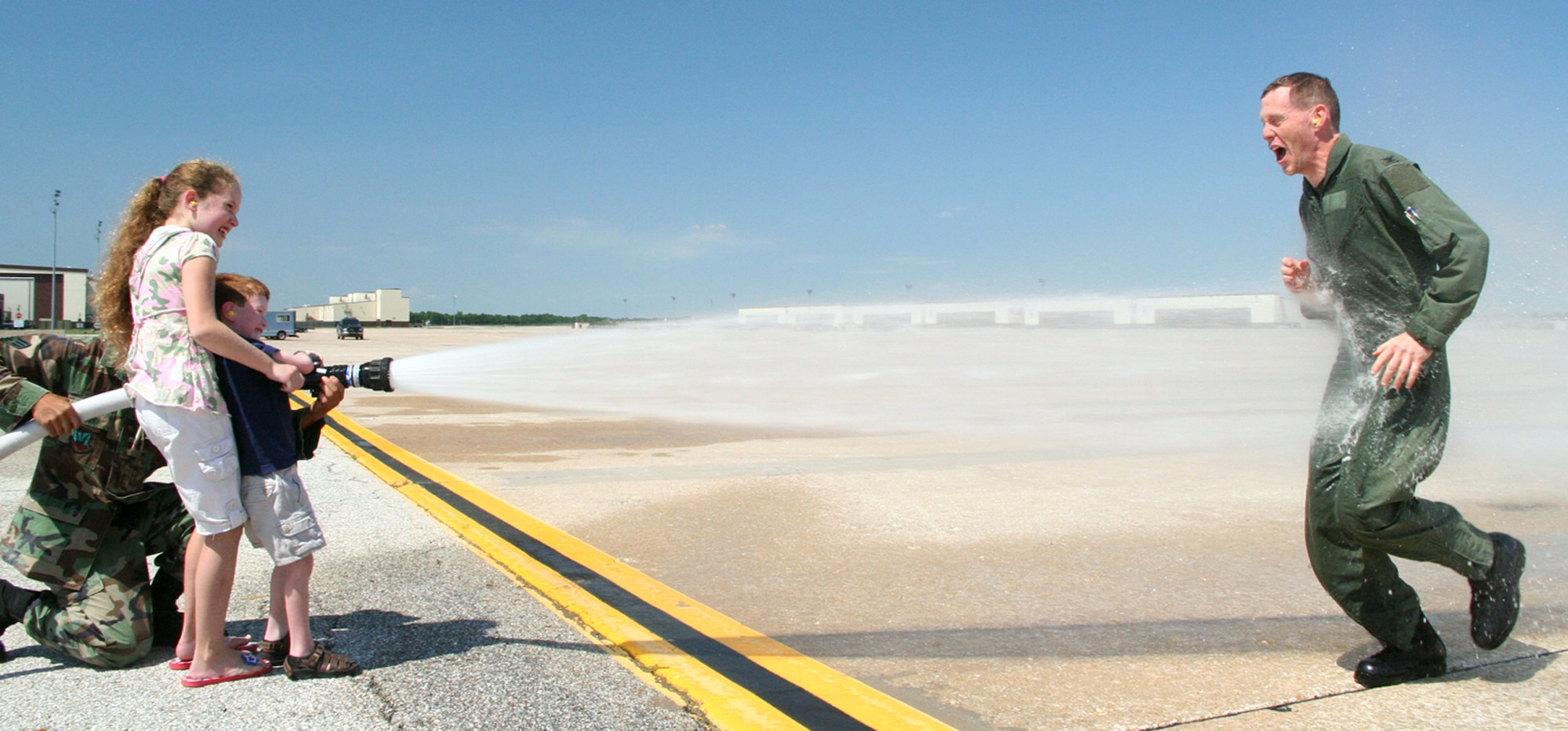 WHITEMAN AIR FORCE BASE, Mo. -- Patricia and Matthew Wheeler, daughter and son of Col. Robert Wheeler, 509th Operations Group commander, drench their father in front of base operations July 6 after the colonel's final B-2 flight at Whiteman. The colonel will assume command of the 2nd Bomb Wing, Barksdale Air Force Base, La., July 26. (U.S. Air Force photo/Airman 1st Class Stephen Linch)