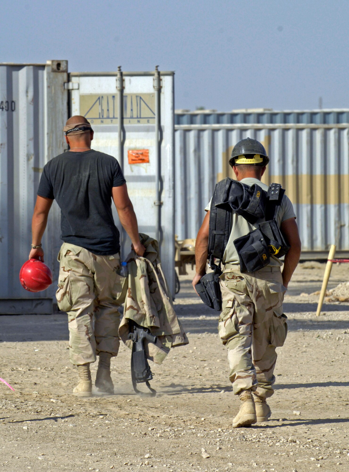 Senior Airman Albert Turner and another Airman carry their tools to their compound after a day of laying roofing material on the first of four tactical operations centers June 22 at Forward Operating Base Kalsu, Iraq. Airman Turner is a structural journeyman with the 557th Expeditionary Red Horse Squadron deployed from the 49th Civil Engineering Squadron at Holliman Air Force Base, N.M. He and his fellow Rapid Engineer Deployable Heavy Operational Repair Squadron Engineers, or RED HORSE, Airmen are forward deployed from Balad Air Base, Iraq, to build four tactical operations centers for the Army's 2nd Brigade combat team, 3rd Infantry Division headquartered here. The 2/3 ID is currently running operations out of tents. The  RED HORSE unit, made up of Air Guard, Reserve and active-duty Airmen, was requested by the Army to come into this "Triangle of Death" location because of their self-suffiency and for the multiple skill sets they bring to a project. (U.S. Air Force photo/Master Sgt. Jim Varhegyi)
