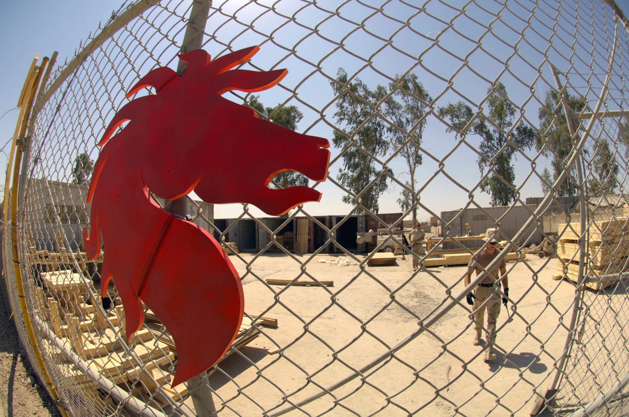 Airmen from the 557th Expeditionary RED HORSE Squadron scrounge for scrap material to cobble together a compound for securing equipment and material which will be used to build tactical operations centers June 22 at Forward Operating Base Kalsu, Iraq. The Rapid Engineer Deployable Heavy Operational Repair Squadron Engineers , or RED HORSE, Airmen are forward deployed from Balad Air Base, Iraq, to build four tactical operations centers for the Army's 2nd Brigade combat team, 3rd Infantry Division headquartered here. The 2/3 ID is currently running operations out of tents. The RED HORSE unit, made up of Air Guard, Reserve and active-duty Airmen, was requested by the Army to come into this "Triangle of Death" location because of their self-suffiency and for the multiple skill sets they bring to a project. (U.S. Air Force photo/Master Sgt. Jim Varhegyi)
