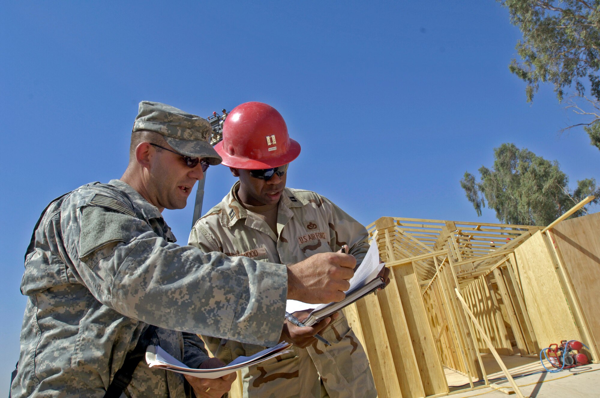 Capt. Kelvin Haywood (right) signs for a shipment of 17 trailers full of supplies from Army Staff Sgt. Chad Kollar June 22 at Forward Operating Base Kalsu, Iraq. Captain Haywood is the engineering flight commander with the 557th Expeditionary RED HORSE Squadron and Sergeant Kollar is logistical convoy commander with the 1207th Transportation Company attached to the 82nd Airborne Brigade. Sergeant Kollar is deployed from the Rhode Island Army National Guard and is based in Talil, Iraq. Captain Haywood is an Air Force reservist deployed from Nellis Air Force Base, Nev. He is in charge of the Rapid Engineer Deployable Heavy Operational Repair Squadron Engineers, or RED HORSE, Airmen who are forward deployed from Balad Air Base, Iraq and tasked with building four tactical operations centers for the Army's 2nd Brigade combat team, 3rd Infantry Division headquartered here. The 2/3 ID are currently running their operations out of tents. The Air Force RED HORSE unit was requested by the Army to come into this "Triangle of Death" location because of their self-suffiency and for the multiple skill sets they bring to a project. (U.S. Air Force photo/Master Sgt. Jim Varhegyi)
