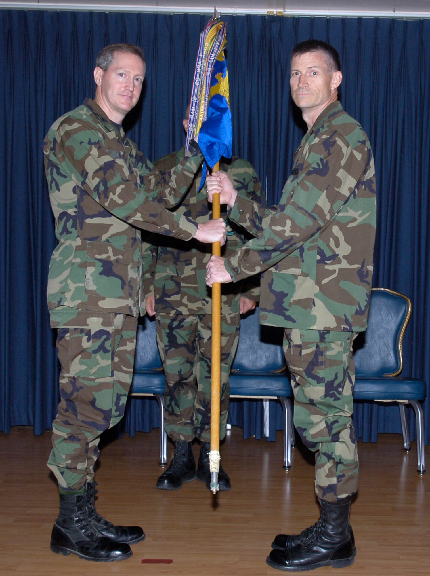 MOUNTAIN HOME AIR FORCE BASE, Idaho -- From left, Col. Thomas Laffey, 366th Mission Support Group commander, passes the 366th Services Squadron guidon to Maj. James Beaty, the squadron's new commander, at a change of command ceremony here July 6. Major Beaty previously served as the military support branch chief at Air Combat Command headquarters, Langley Air Force Base, Va. Lt. Col. Anthony Lanuzo, the squadron’s former commander, left Mountain Home to join the Air Force Services Agency at the Pentagon. (Air Force photo/Airman 1st Class Ryan Crane)