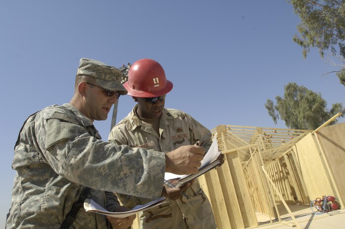 Capt. Kelvin Haywood (right), engineering flight commander with the 557th Expeditionary Red Horse Squadron (ERHS) whose unit is deployed from the 555th RHS at Nellis AFB, signs for a shipment of 17 trailers full of supplies on Friday, June 22, from U. S. Army Staff Sgt. Chad Kollar, logistical convoy commander with the 1207th Transportation Company attached to the 82nd Airborne Brigade. Sergeant Kollar was a very welcome site to the RED HORSE commander because of the difficulty in receiving supplies moving through Iraq. Sergeant Kollar is deployed from the Rhode Island Army National Guard and is based in Talil, Iraq. Captain Haywood is an Air Force Reservist deployed from Nellis Air Force Base, Nev. He is in charge of the Rapid Engineer Deployable Heavy Operational Repair Squadron Engineers RED HORSE Airmen who are forward deployed from Balad Air Base, Iraq and tasked with building four tactical operations centers for the Army's 2nd Brigade combat team, 3rd Infantry Division headquartered here. The 2/3 ID are currently running their operations out of tents. The Air Force RED HORSE unit was requested by the Army to come into this "Triangle of Death" location because of their self-suffiency and for the multiple skill sets they bring to a project. Besides the TOCs the RED HORSE Airmen are working on several other projects at the FOB. (U.S. Air Force photo by Master Sgt. Jim Varhegyi)