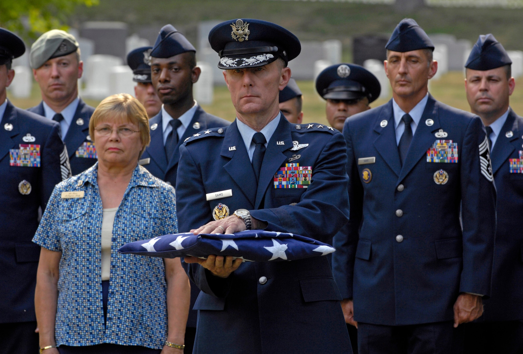 Inspector General of the Air Force Lt. Gen. Ronald F. Sams holds the United States flag to present to the family of former Chief Master Sergeant of the Air Force Gary R. Pfingston at his burial site July 6 at Arlington National Cemetery, Va.  The 10th CMSAF was born in Evansville, Ind., and entered the Air Force in February 1962. He passed away June 23 in San Antonio. (U.S. Air Force photo/Senior Airman Rusti Caraker)